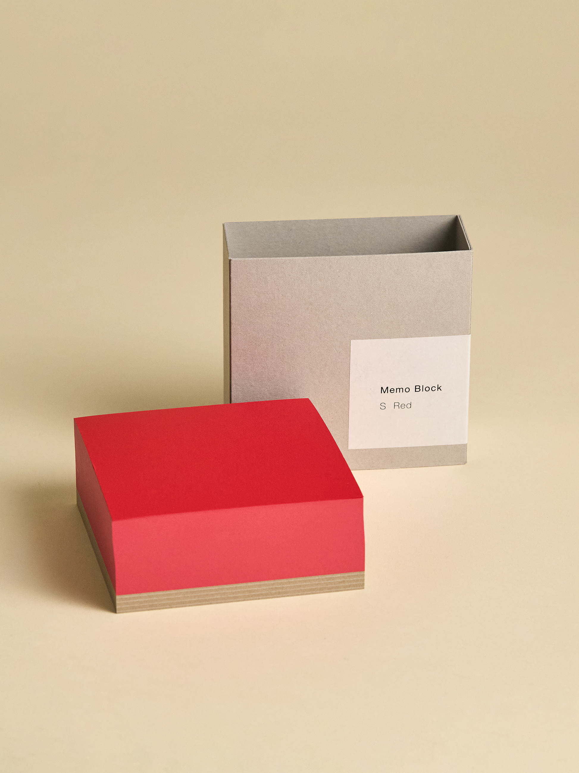 Red memoblock with packaging on the outside next to it on light background