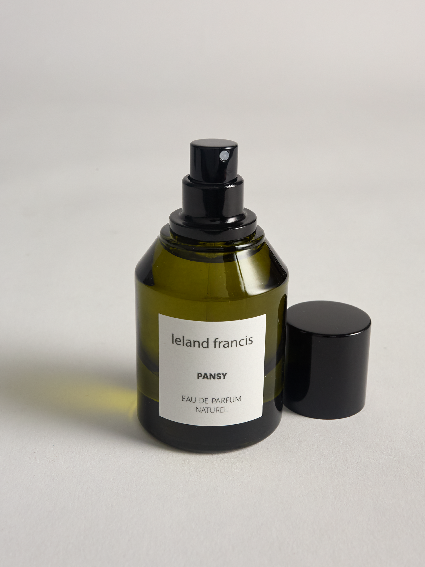 Green perfume bottle labeled 'Ieland Francis Pansy' on a light gray background