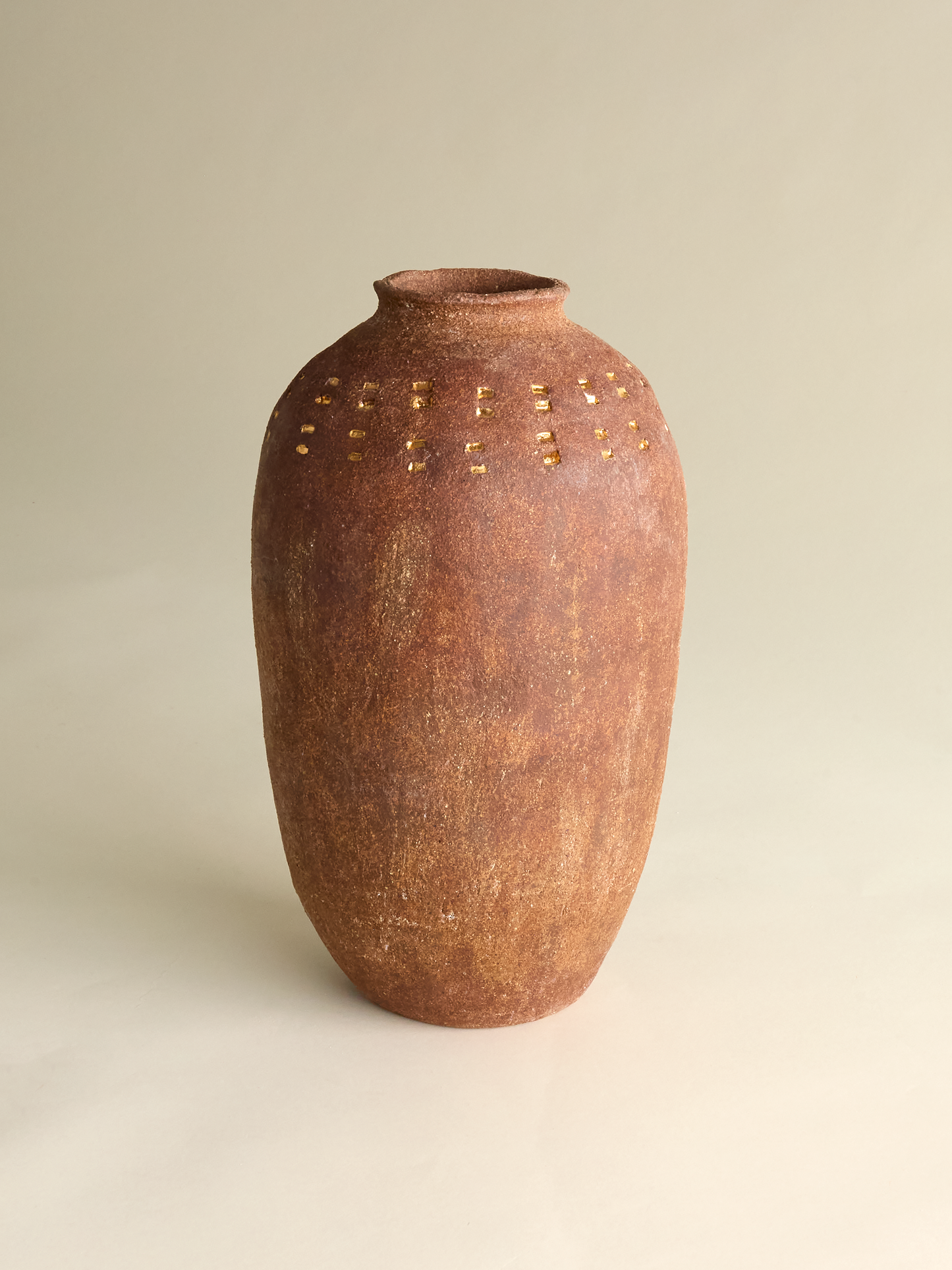Pascale Vaquette full perspective of burnt sienna vase with gold markings on light background