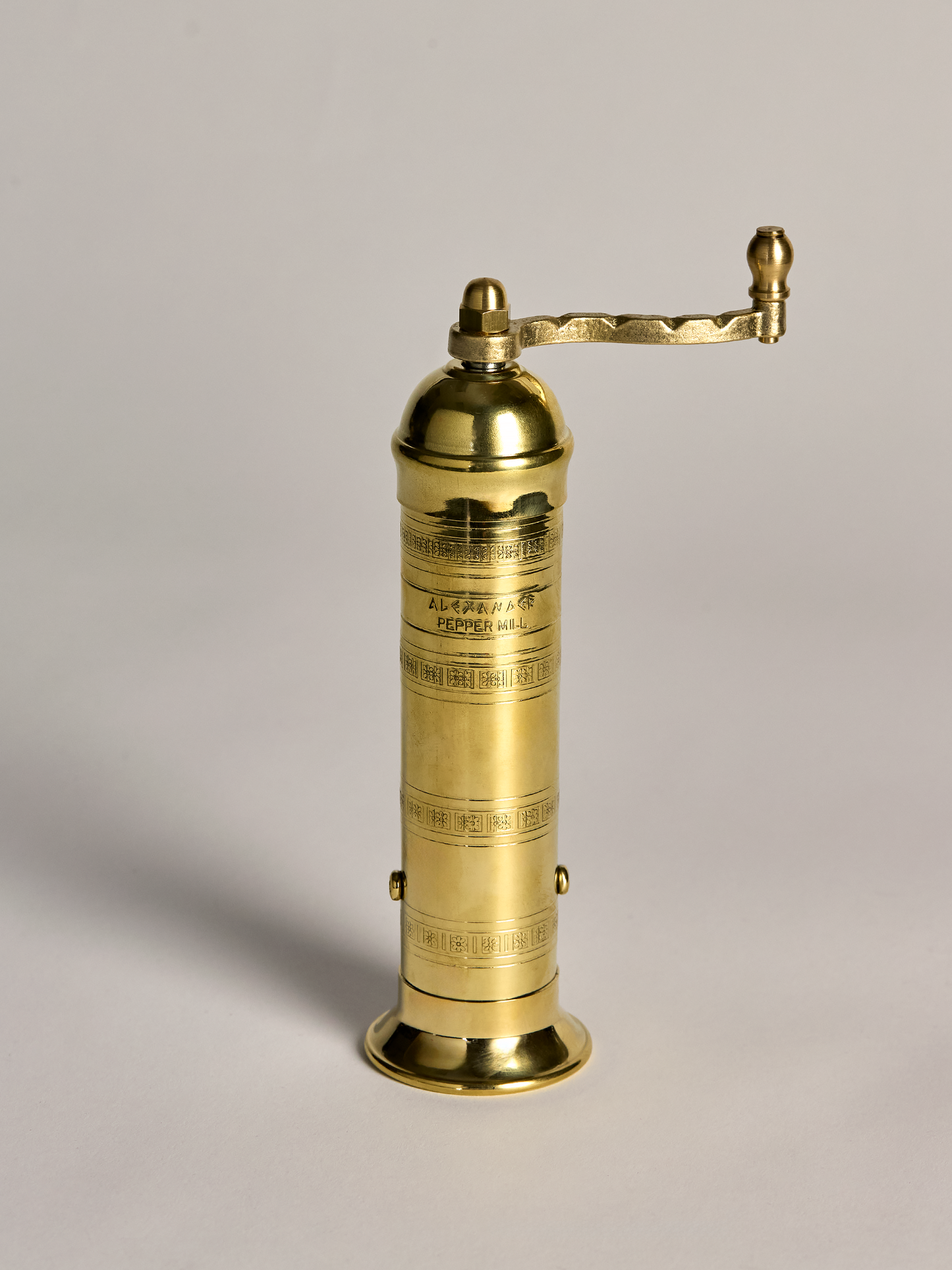 Brass pepper grinder on a light gray background