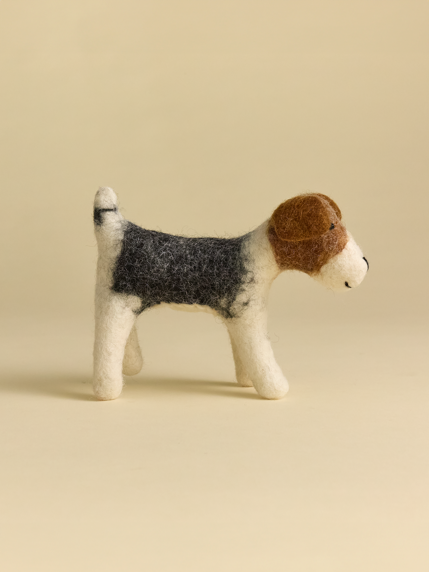 Side view of felt dog, grey brown and white