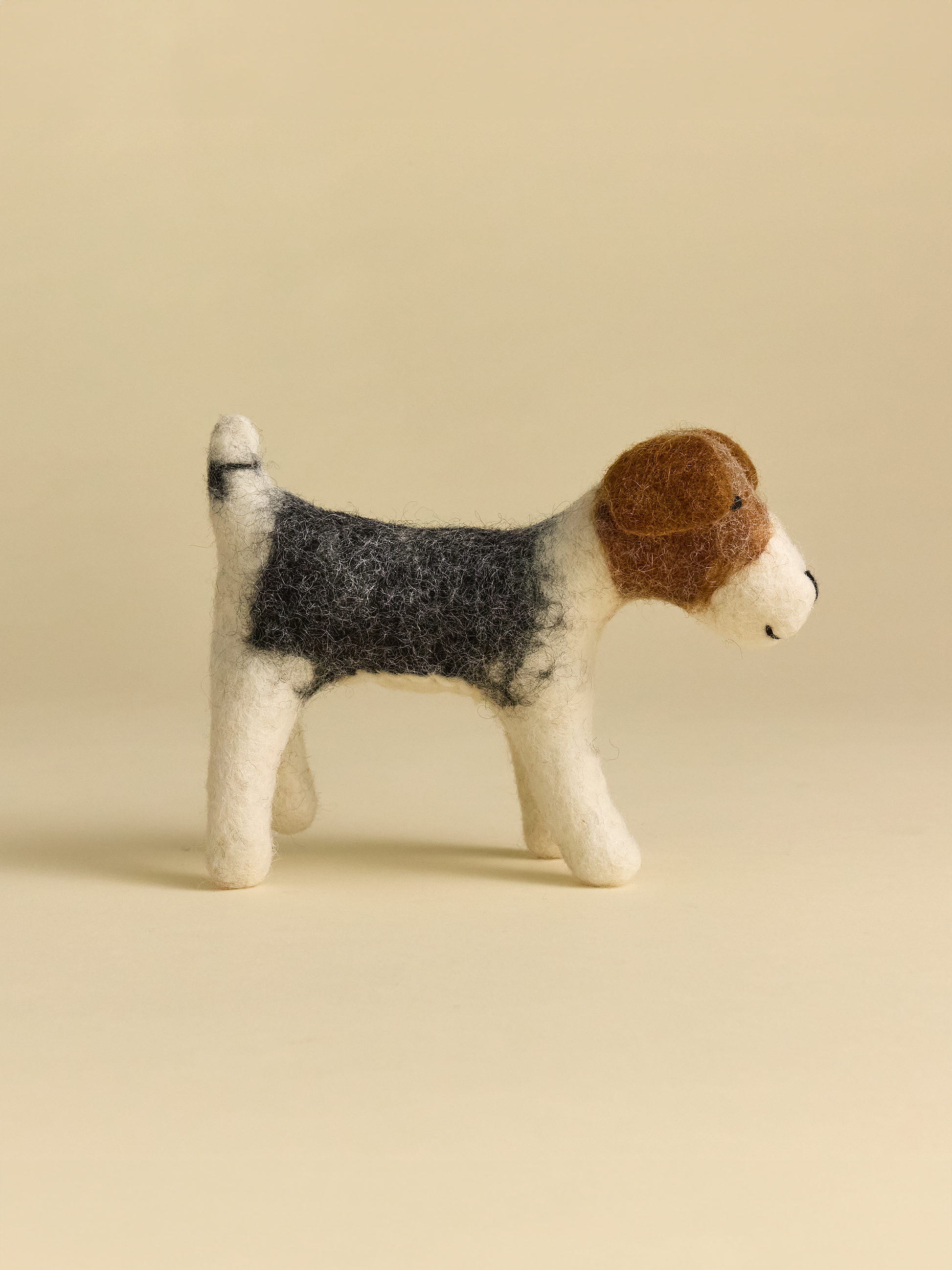 Side view of felt dog, grey brown and white