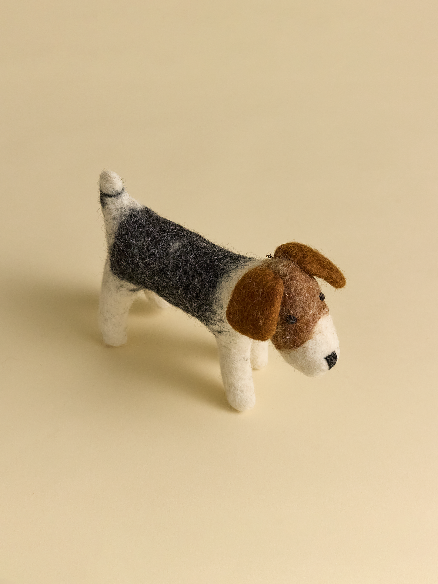 Top view of small felt dog on neutral background