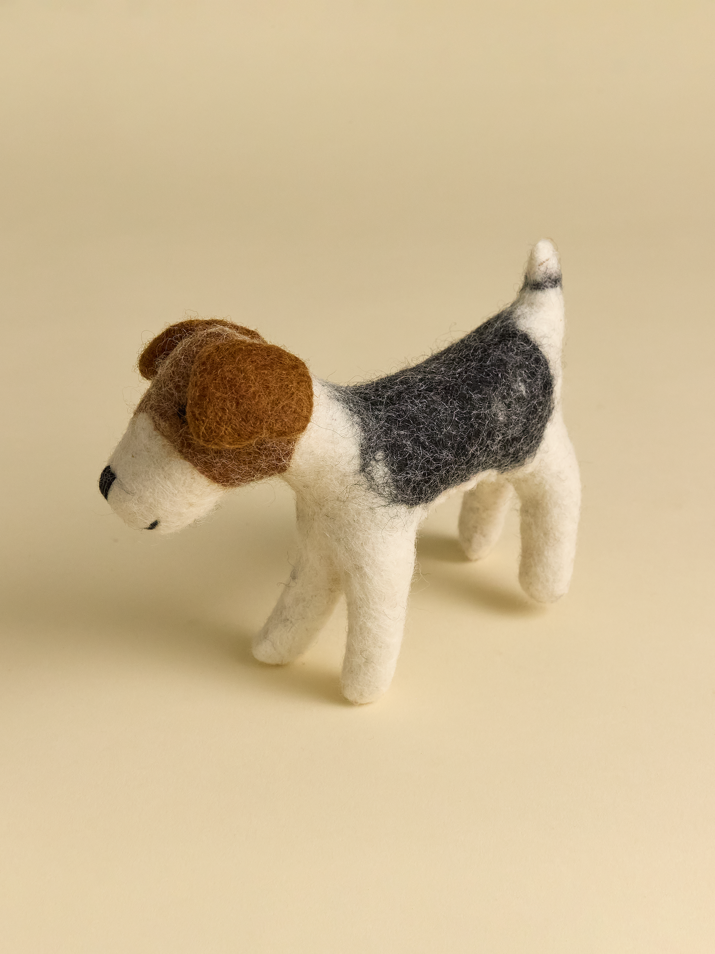 Small felt dog with tail and ears on neutral background