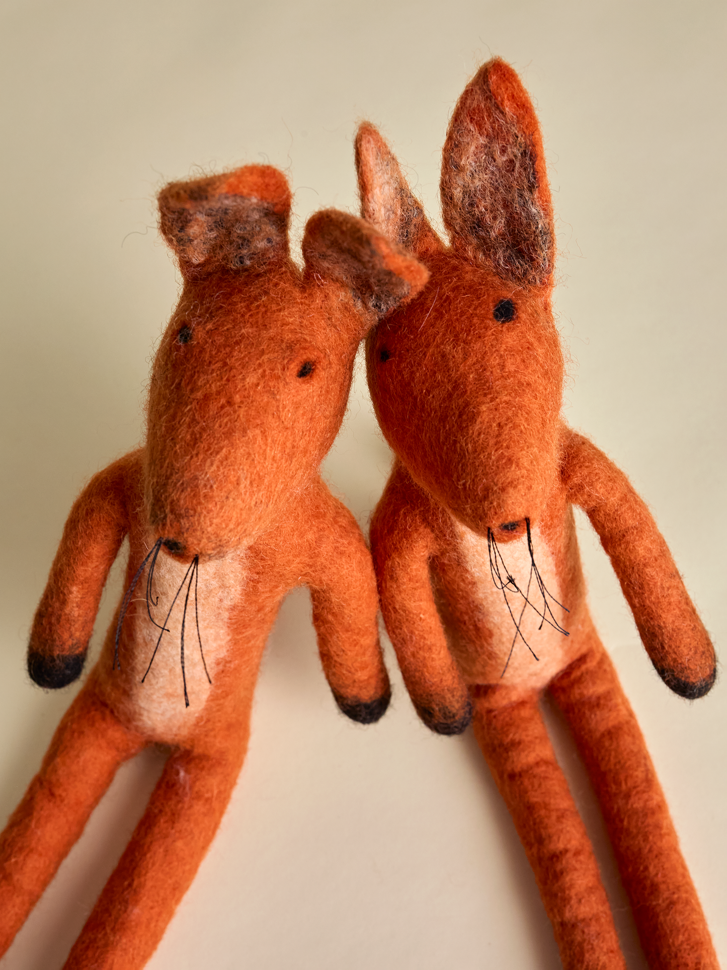 Top view of two felt foxes with whiskers