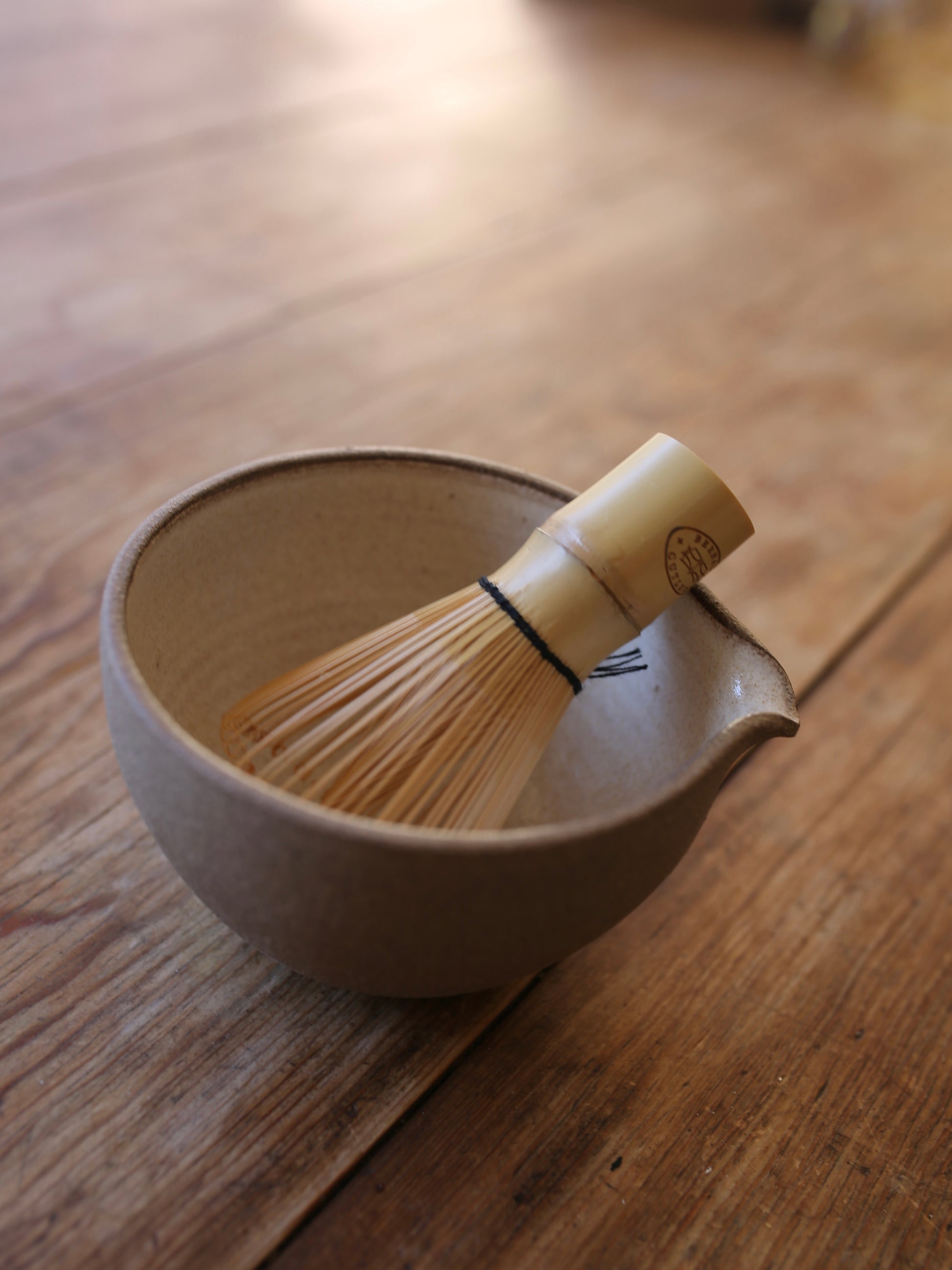 Bamboo whisk in a ceramic bowl on a wooden surface