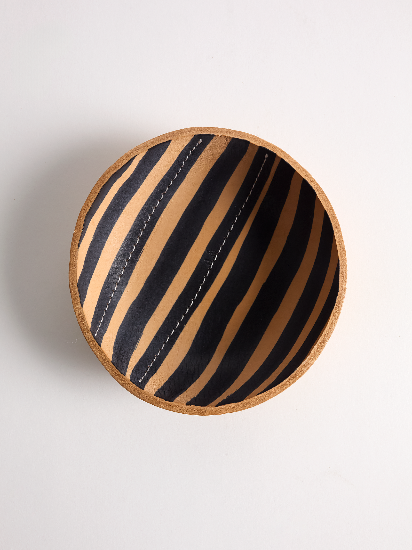 Black striped leather bowl design on a light gray background