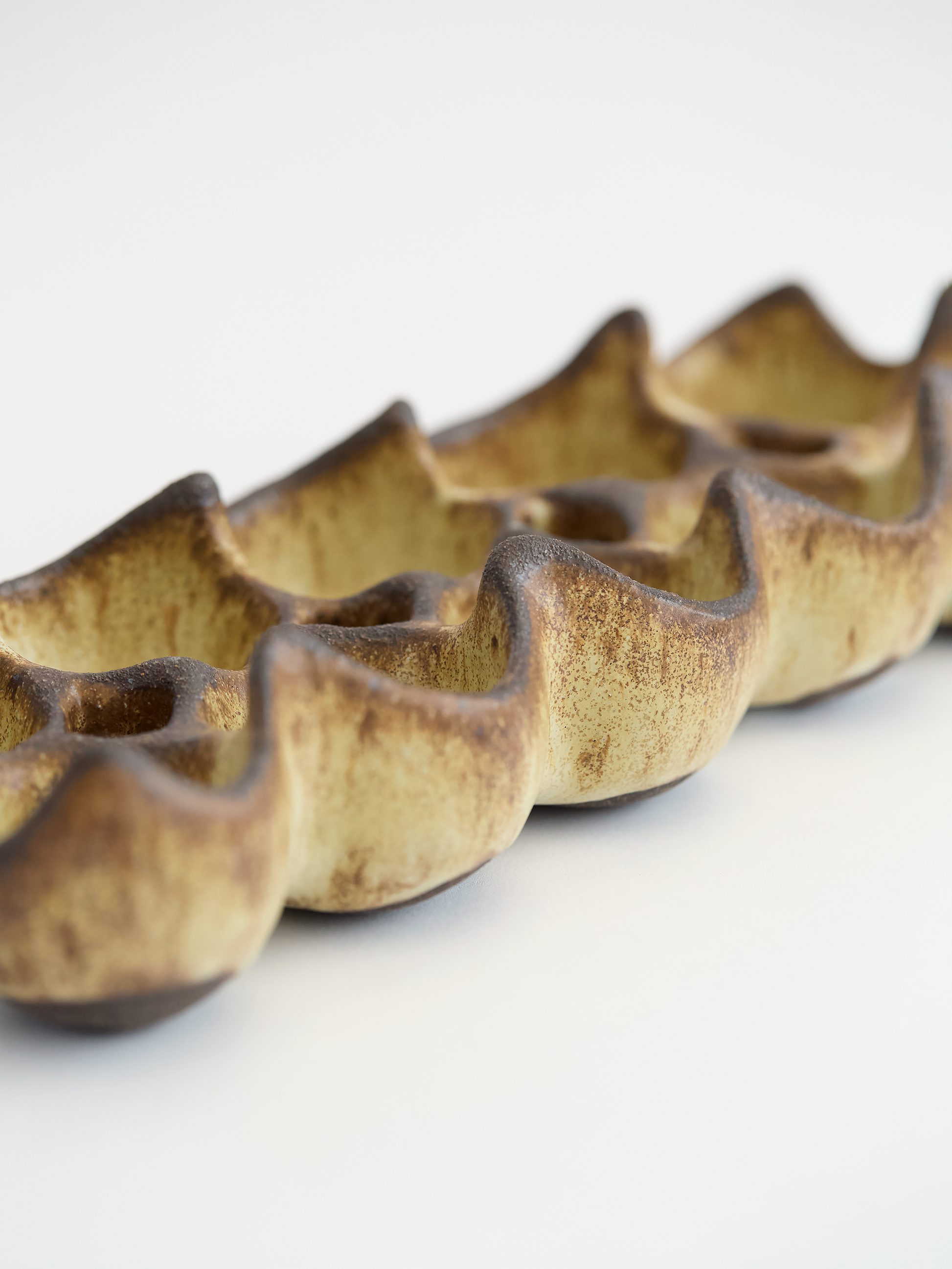 Olive brown ceramic egg holder  with high edges on a white background