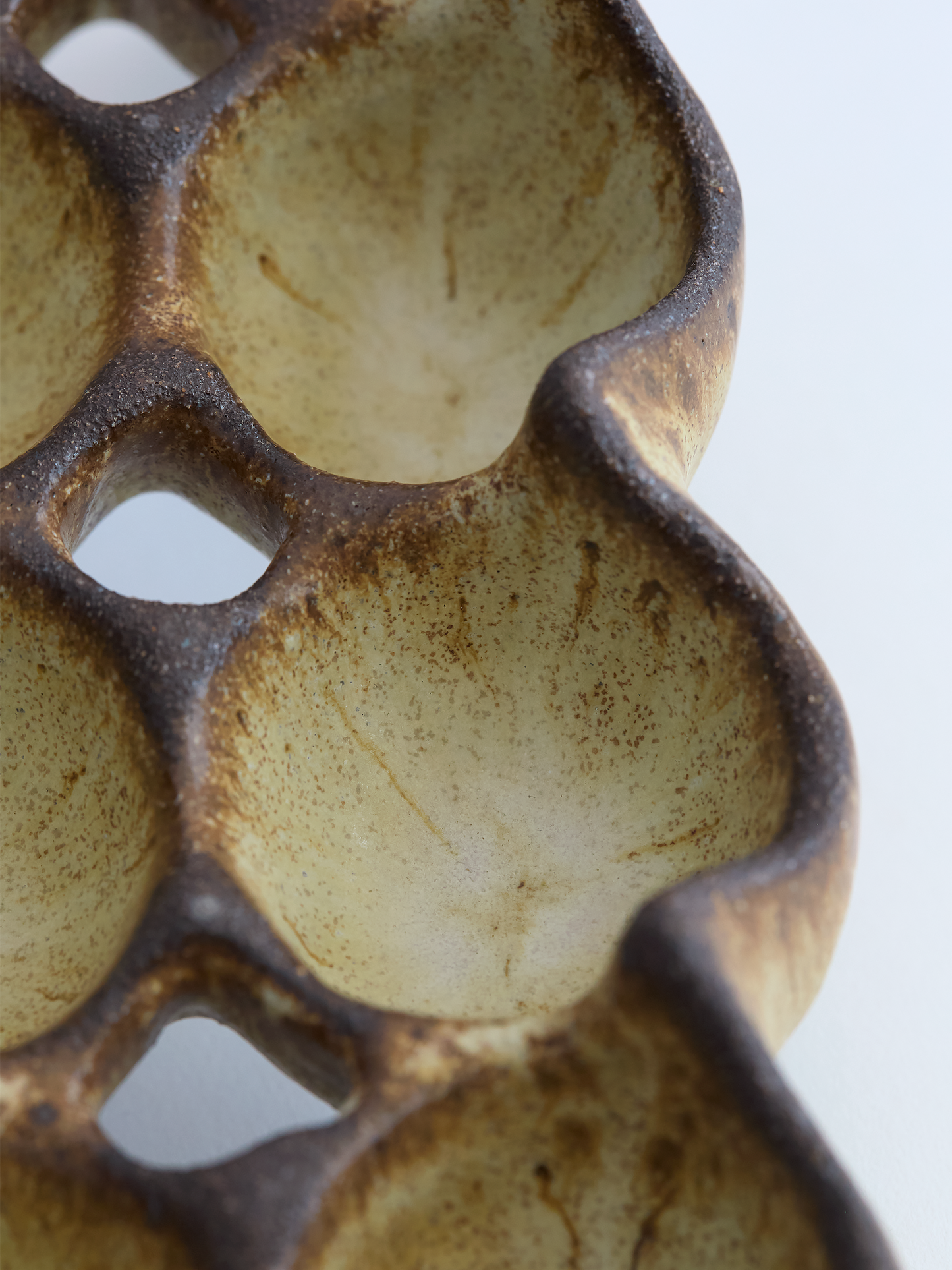 Close-up of a textured ceramic egg holder with brown and beige colors on a white background