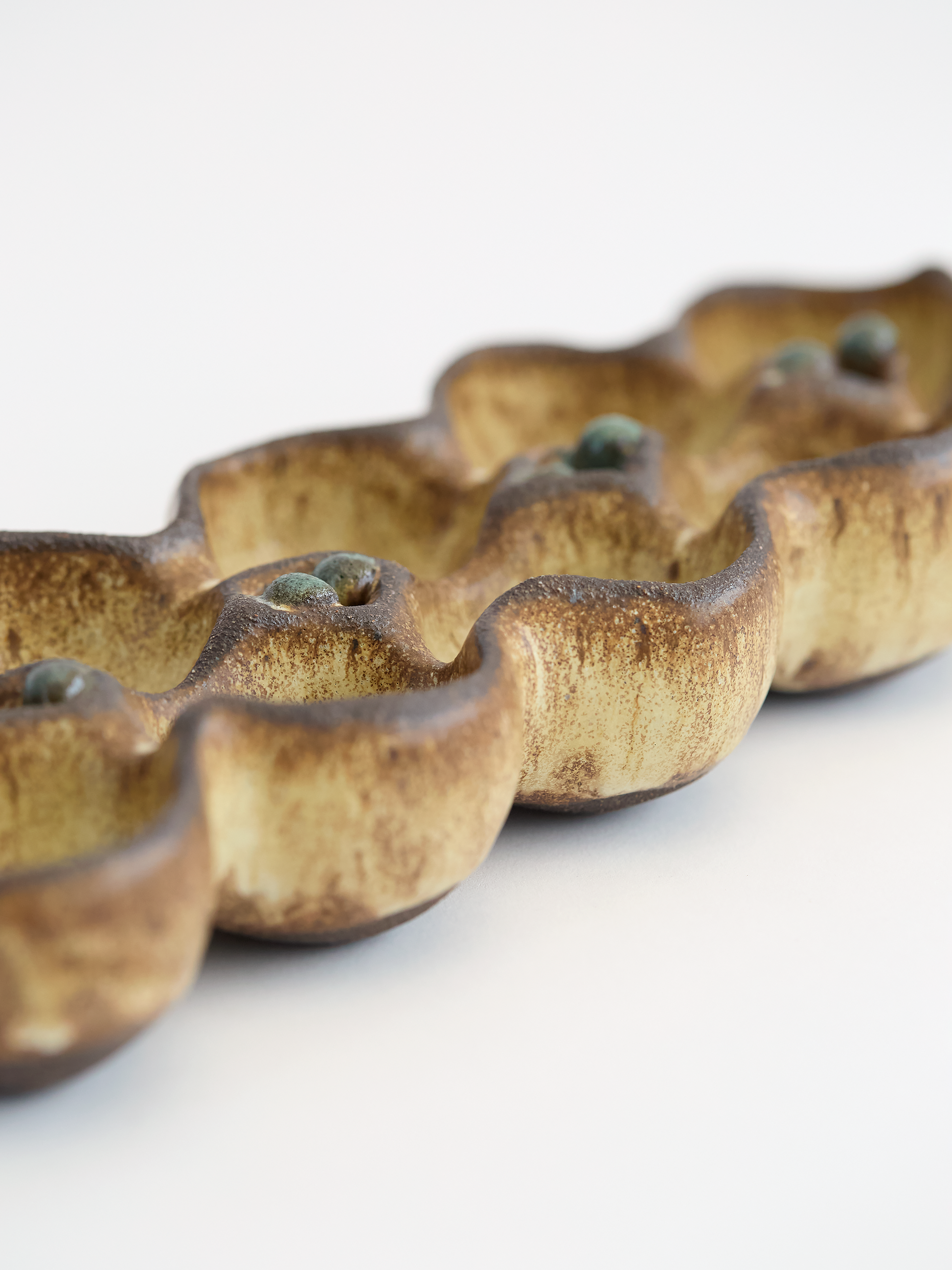 Olive brown ceramic egg holder  with rounded edges on a white background