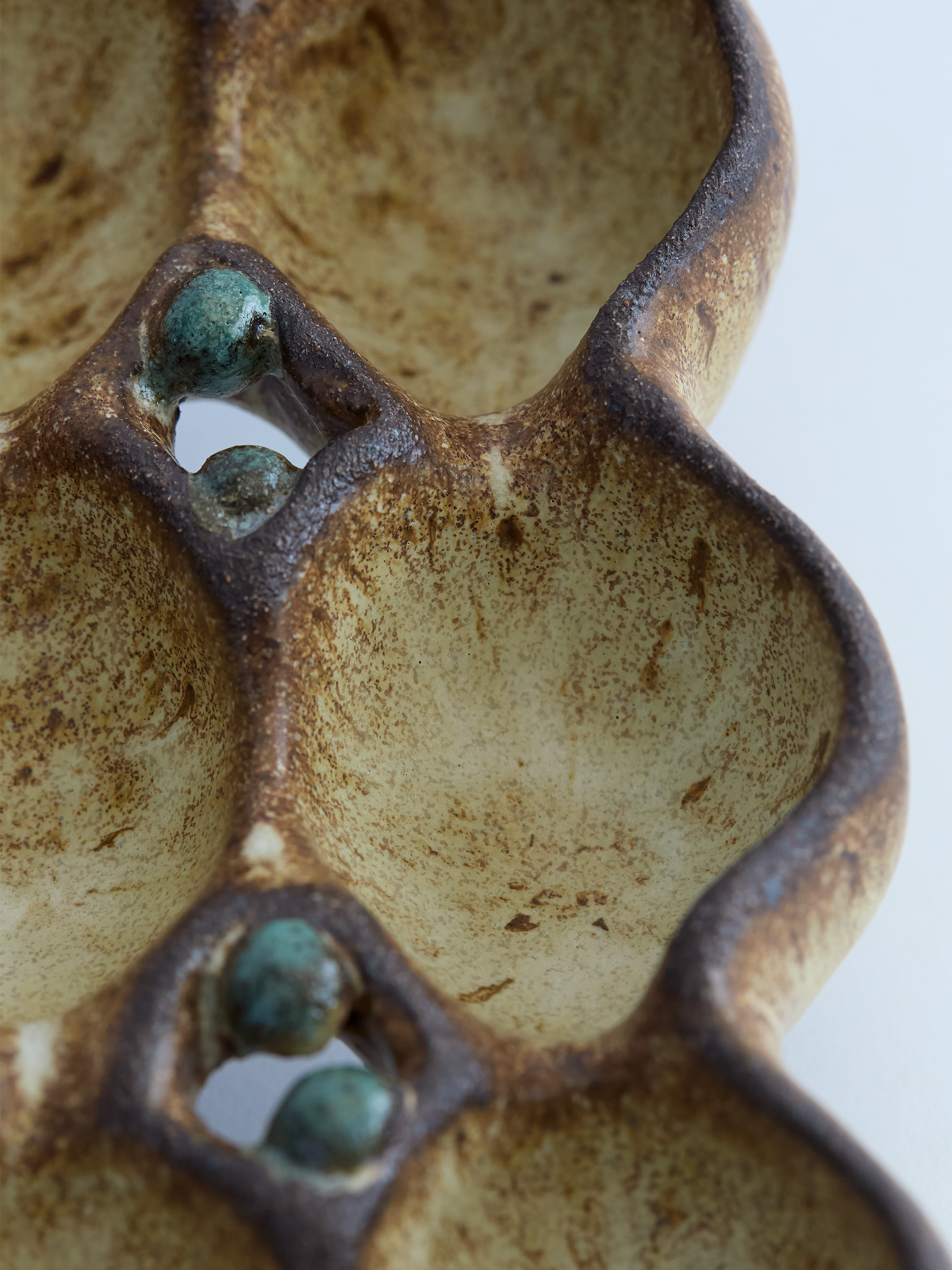 Close-up of a ceramic egg holder with textured surface and green accents on a white background