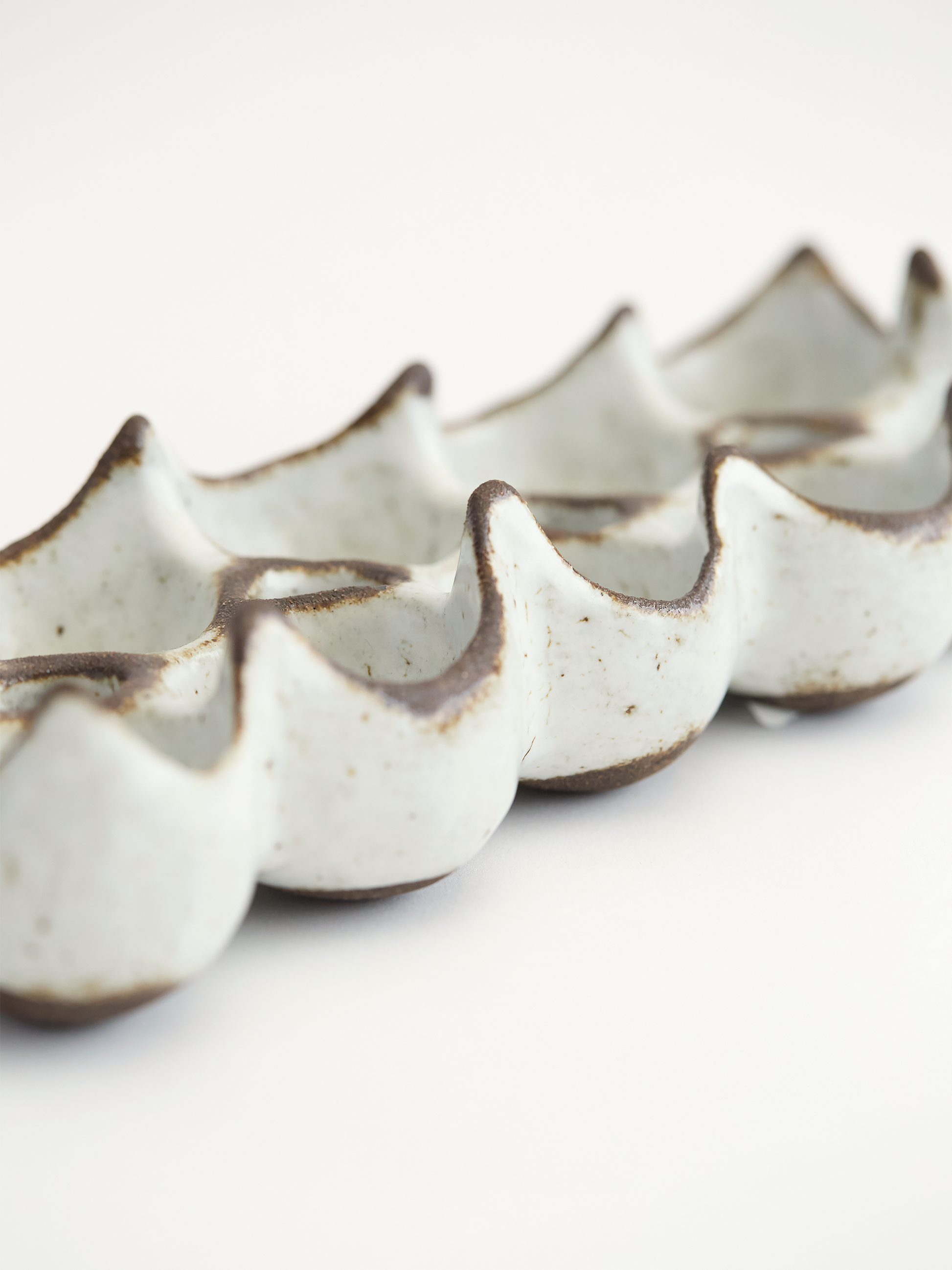 White ceramic egg holder  with high brown edges on a white background