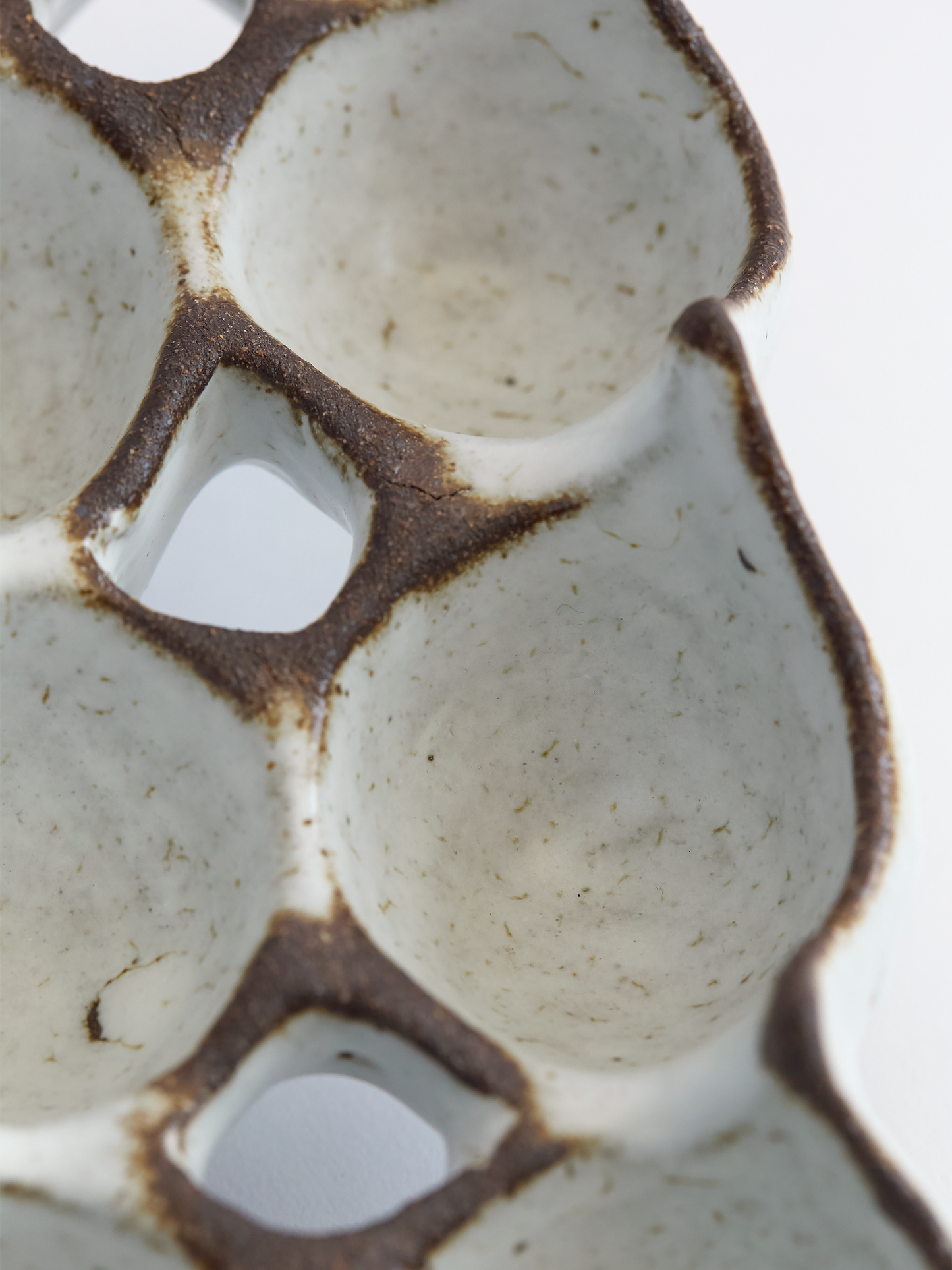Close-up of a ceramic egg carton with brown rim on a white background