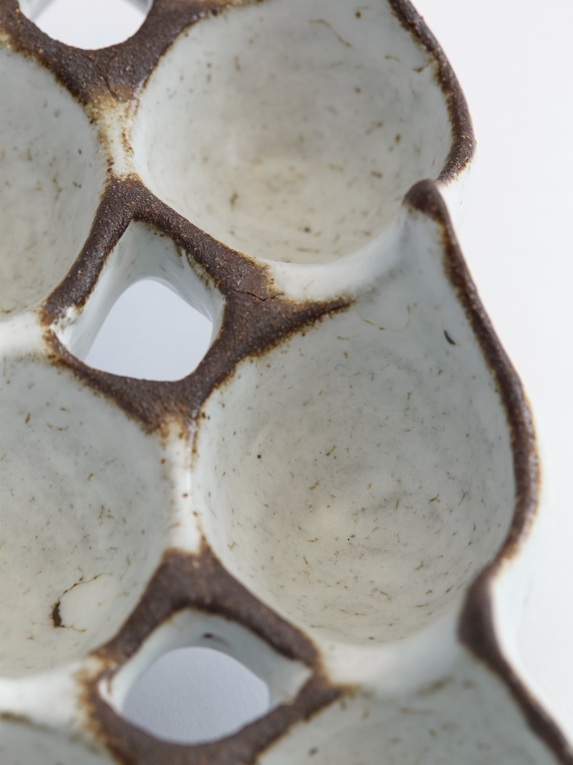 Close-up of a ceramic egg carton with brown rim on a white background