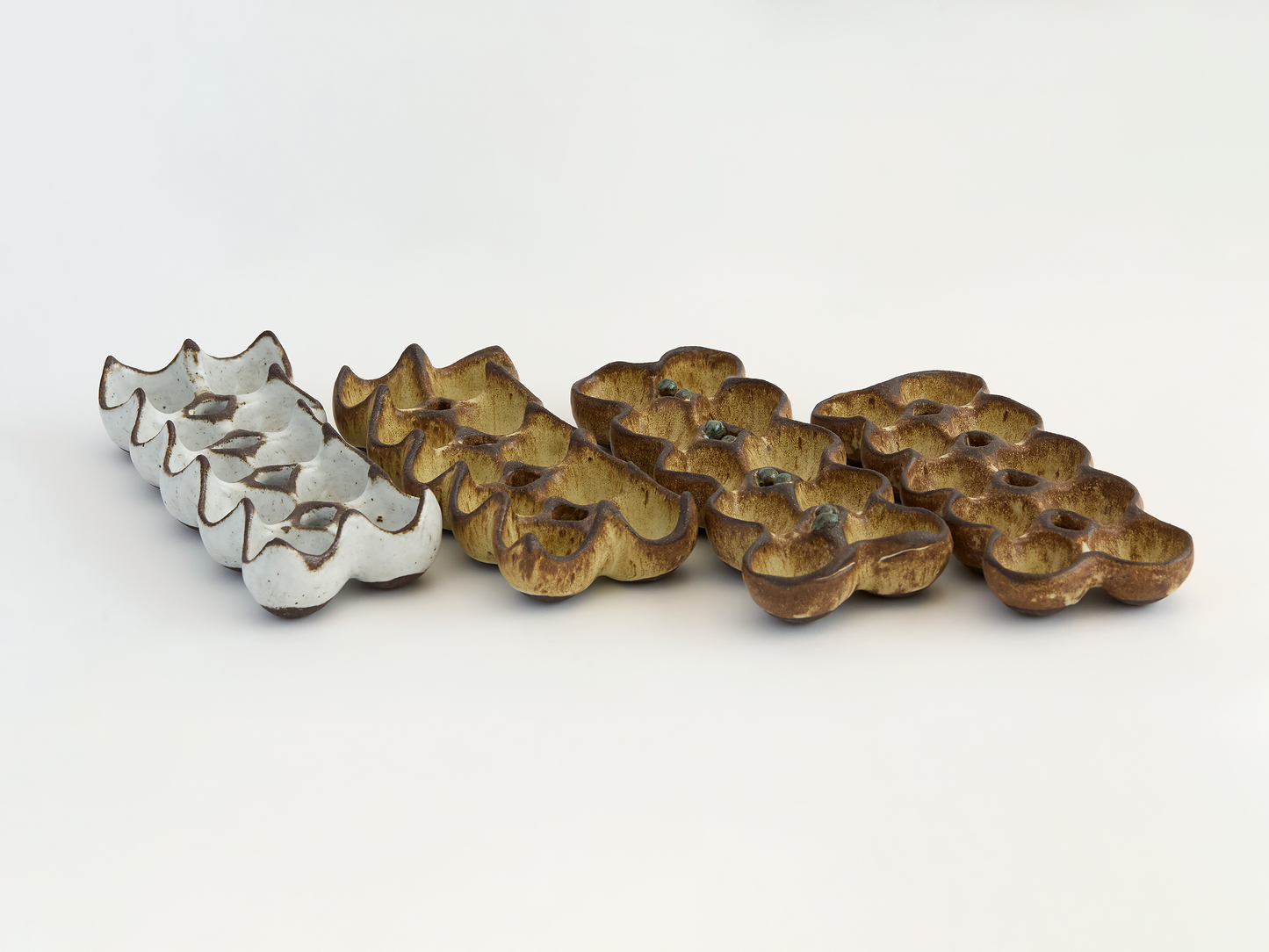 Various rustic colored ceramic egg holders on a light background