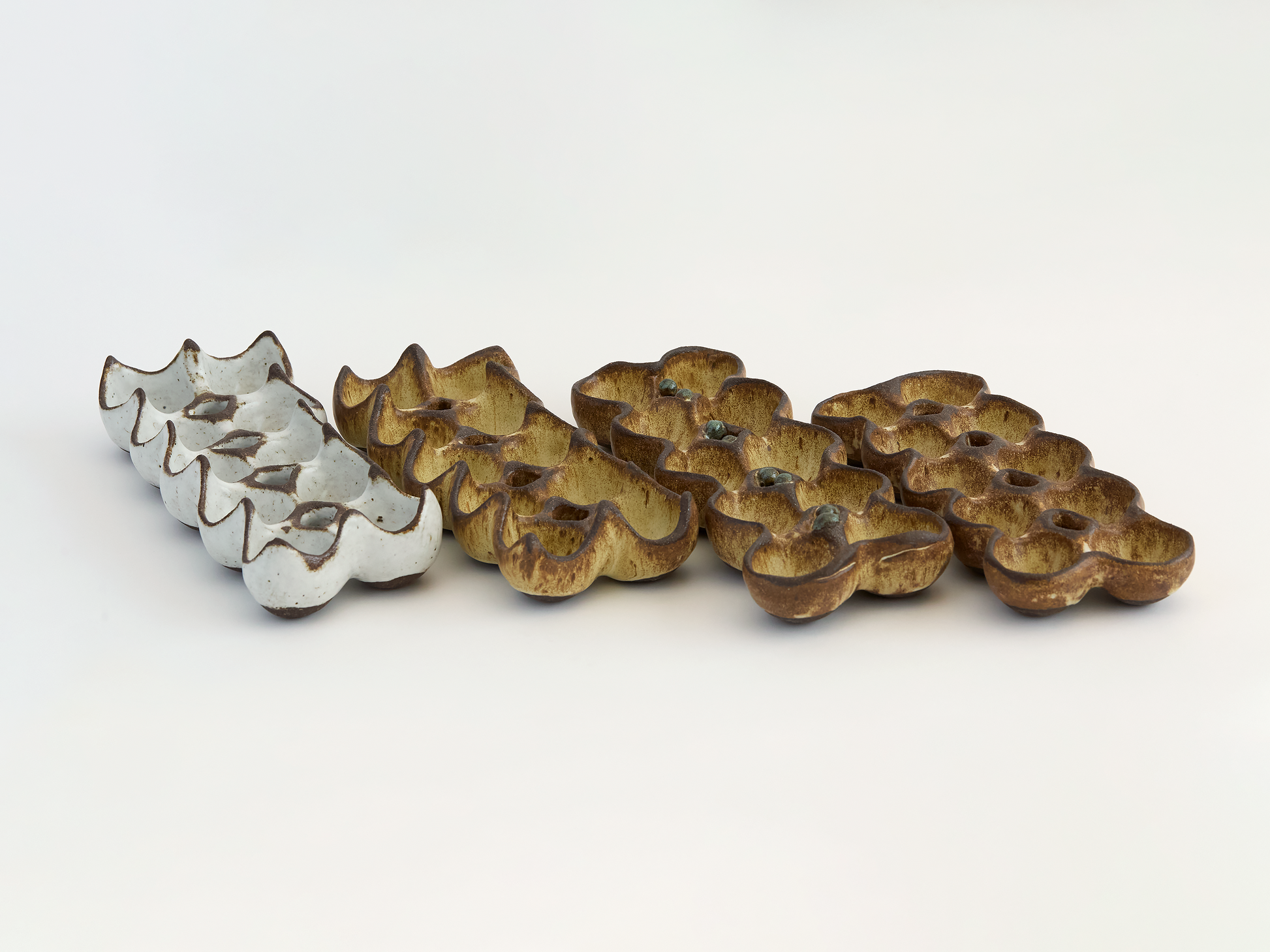 Various rustic colored ceramic egg holders on a light background