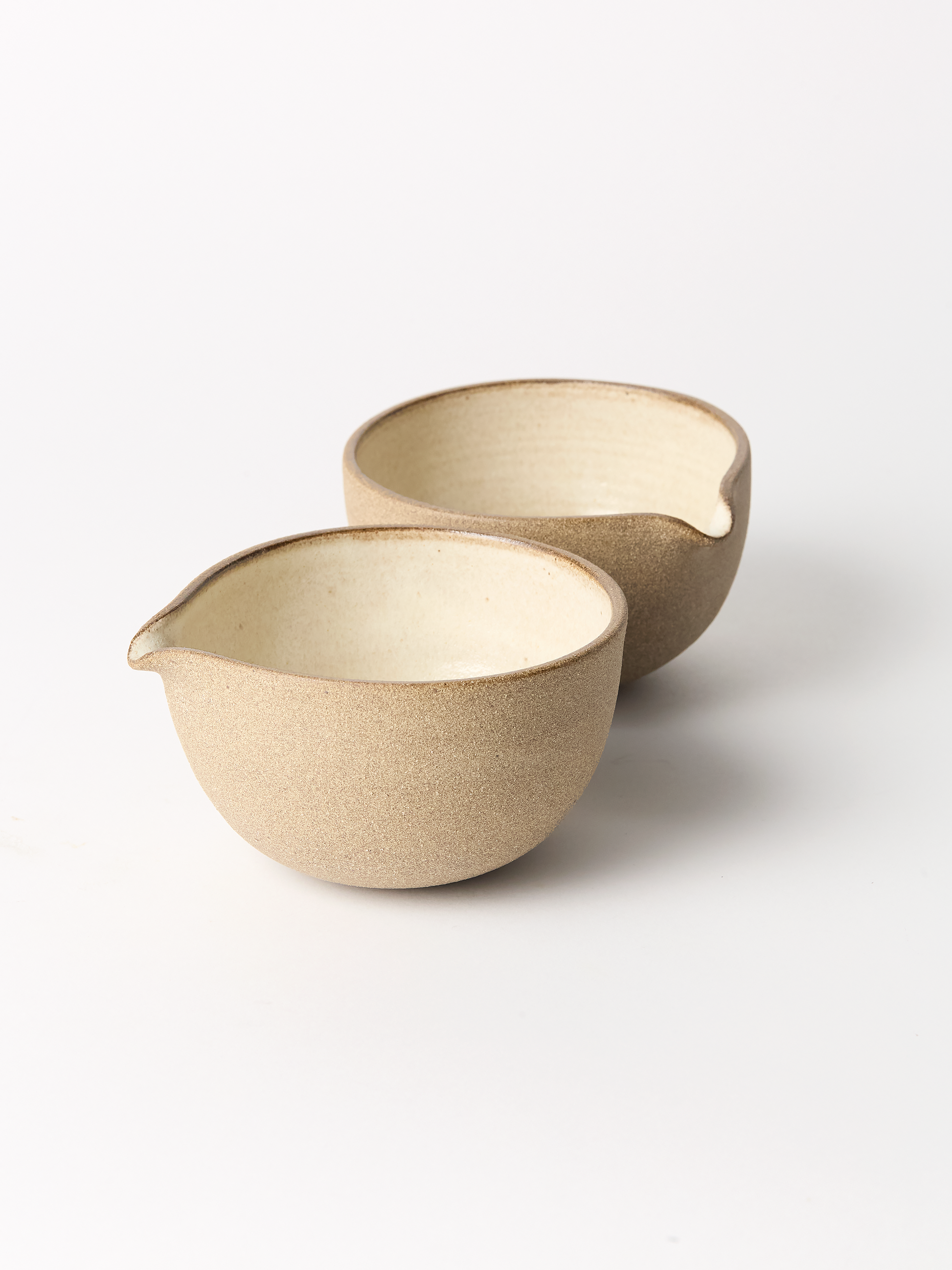 Two beige ceramic bowls on a white background