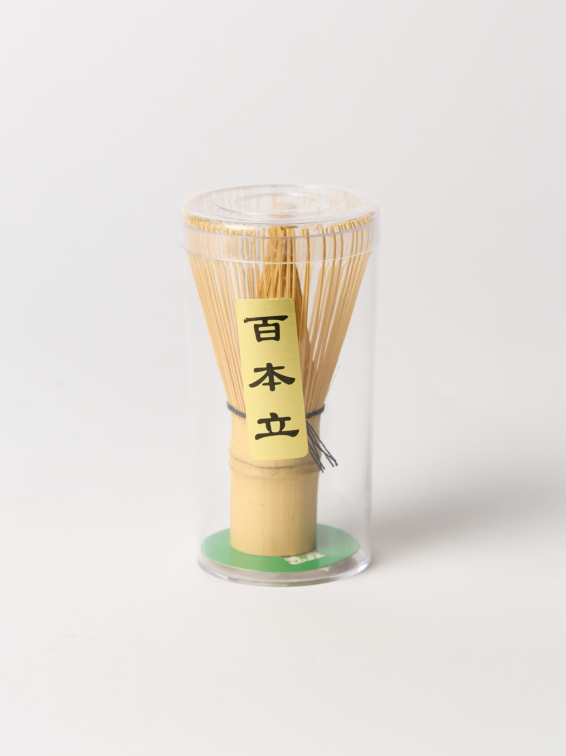 Bamboo matcha whisk set in a clear cylindrical container on a white background