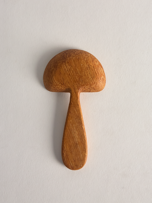 small Wooden mushroom shaped spoon back on a light gray background