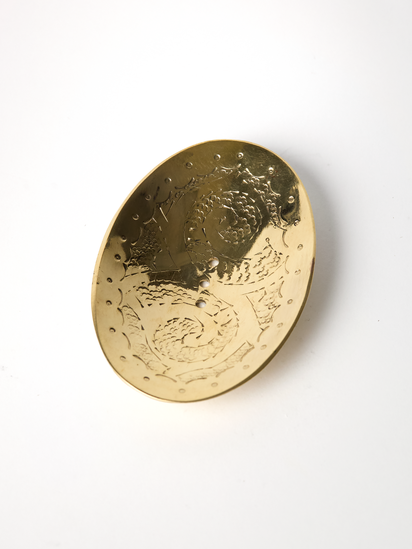 unlaquered brass soap dish with intricate patterns on a white background