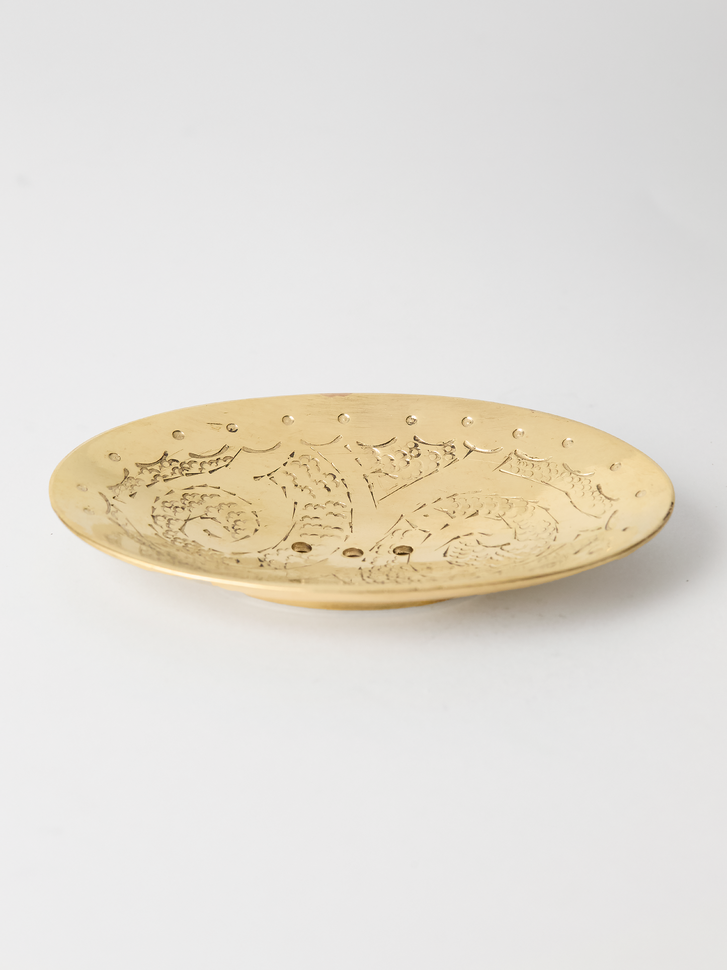 unlaquered brass soap dish embossed design on a light gray background