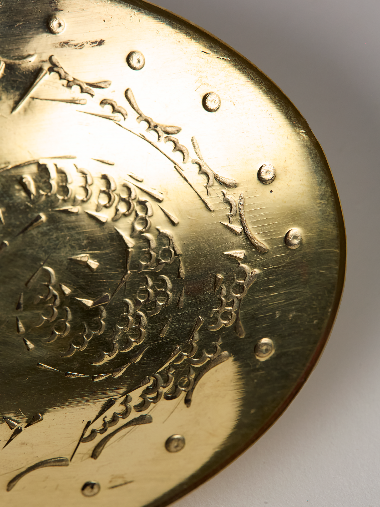 Close-up of a unlaquered brass soap dish wit intricate patterns on a white background
