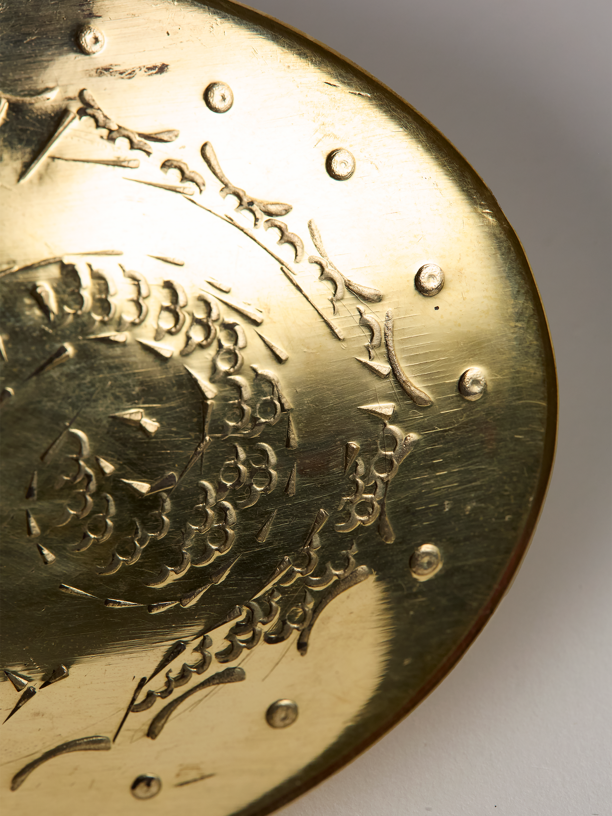 Close-up of a unlaquered brass soap dish wit intricate patterns on a white background