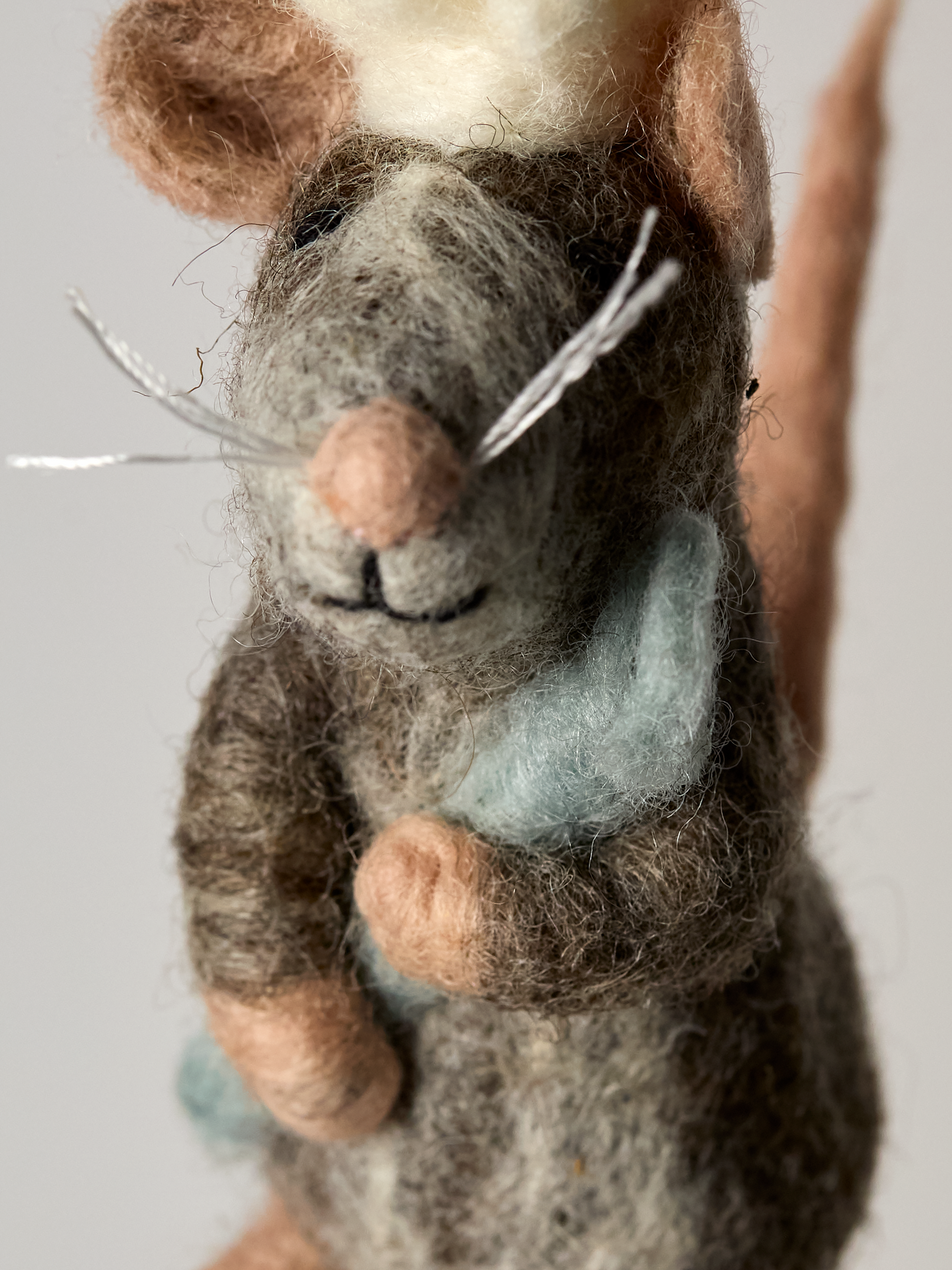 Close-up of Felted finger puppet Chef mouse toy with a blue chef spoon on a gray background