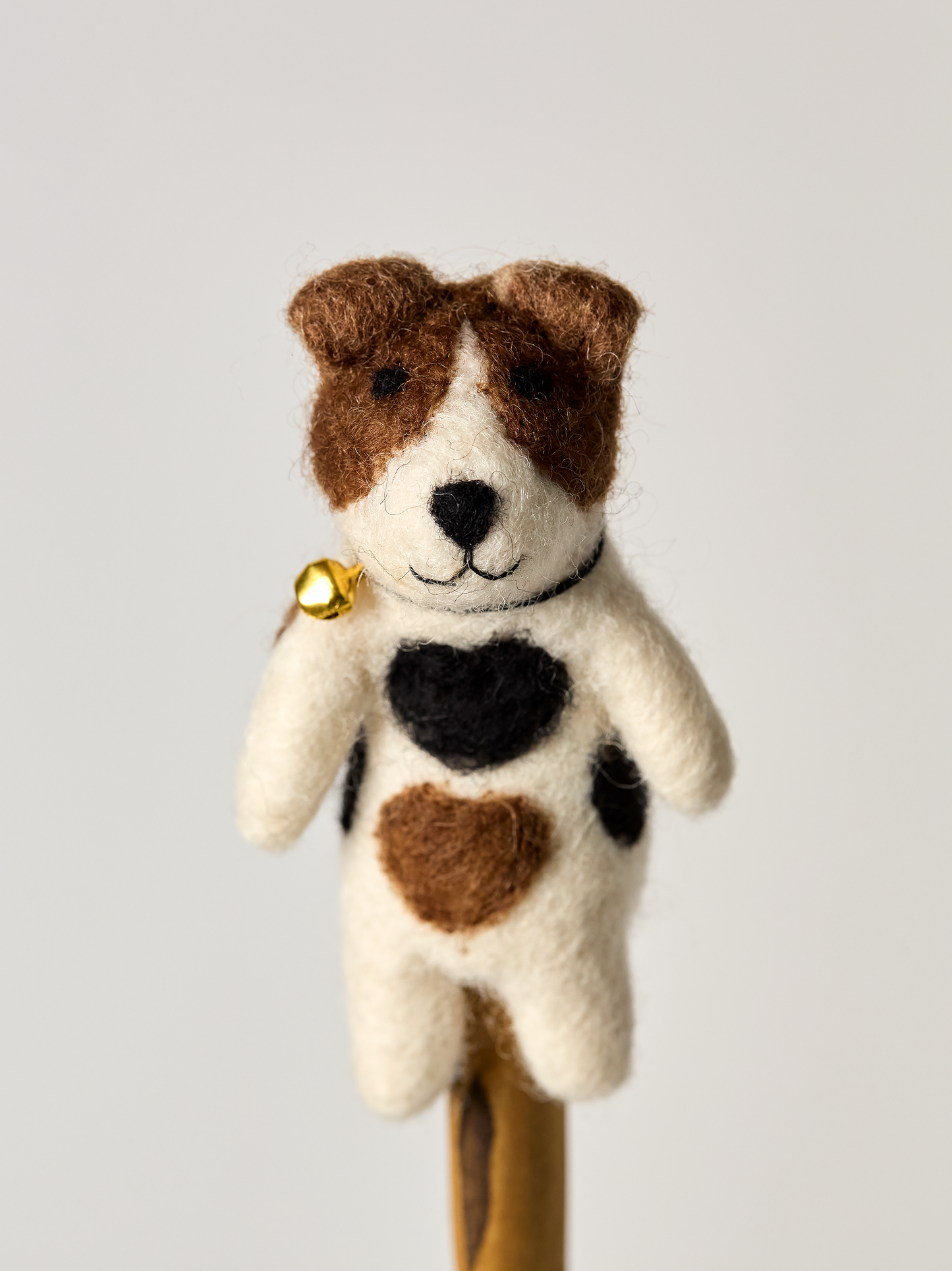 Jack Russel finger puppet dog toy with a heart pattern and a bell on a white background