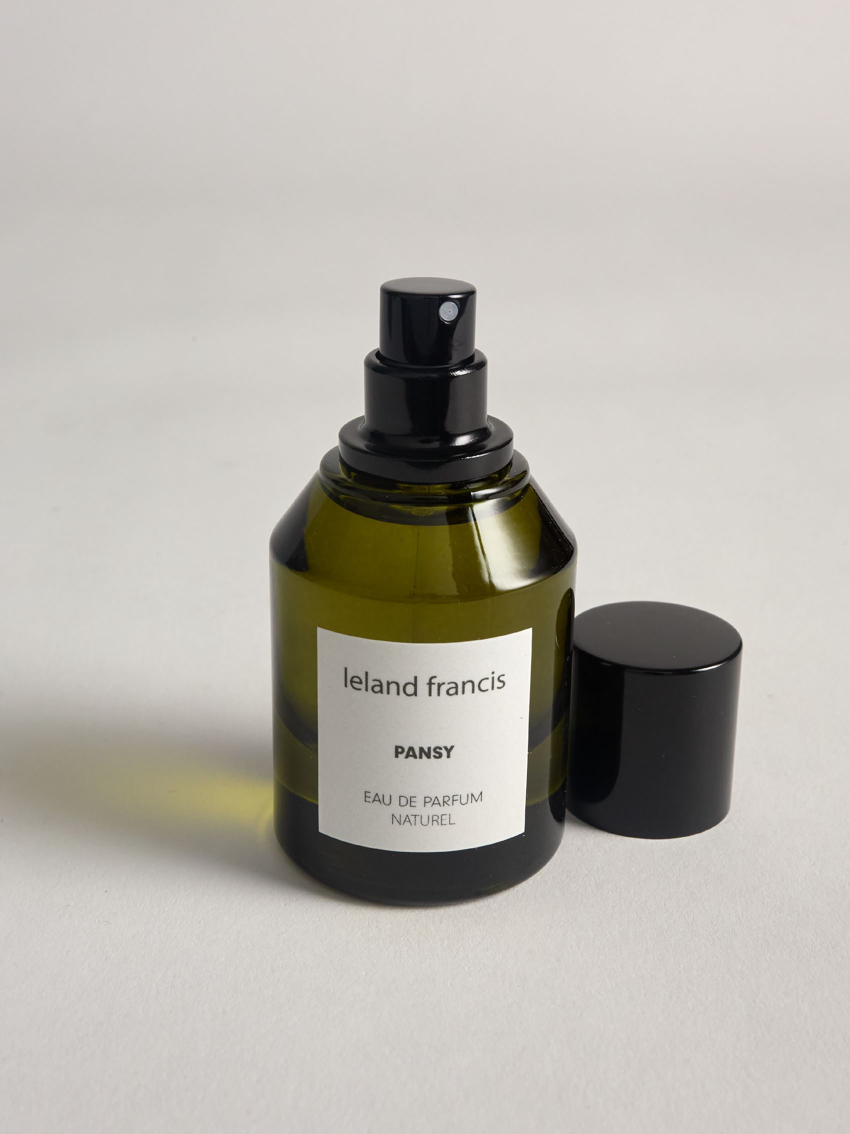 Green perfume bottle labeled 'Ieland Francis Pansy' on a light gray background
