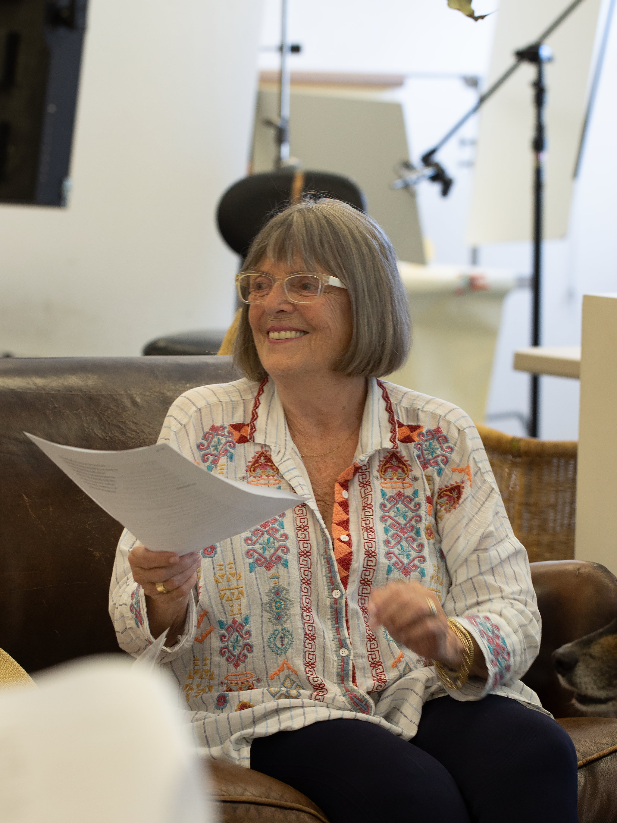 Woman sitting on a couch holding papers in an indoor setting
