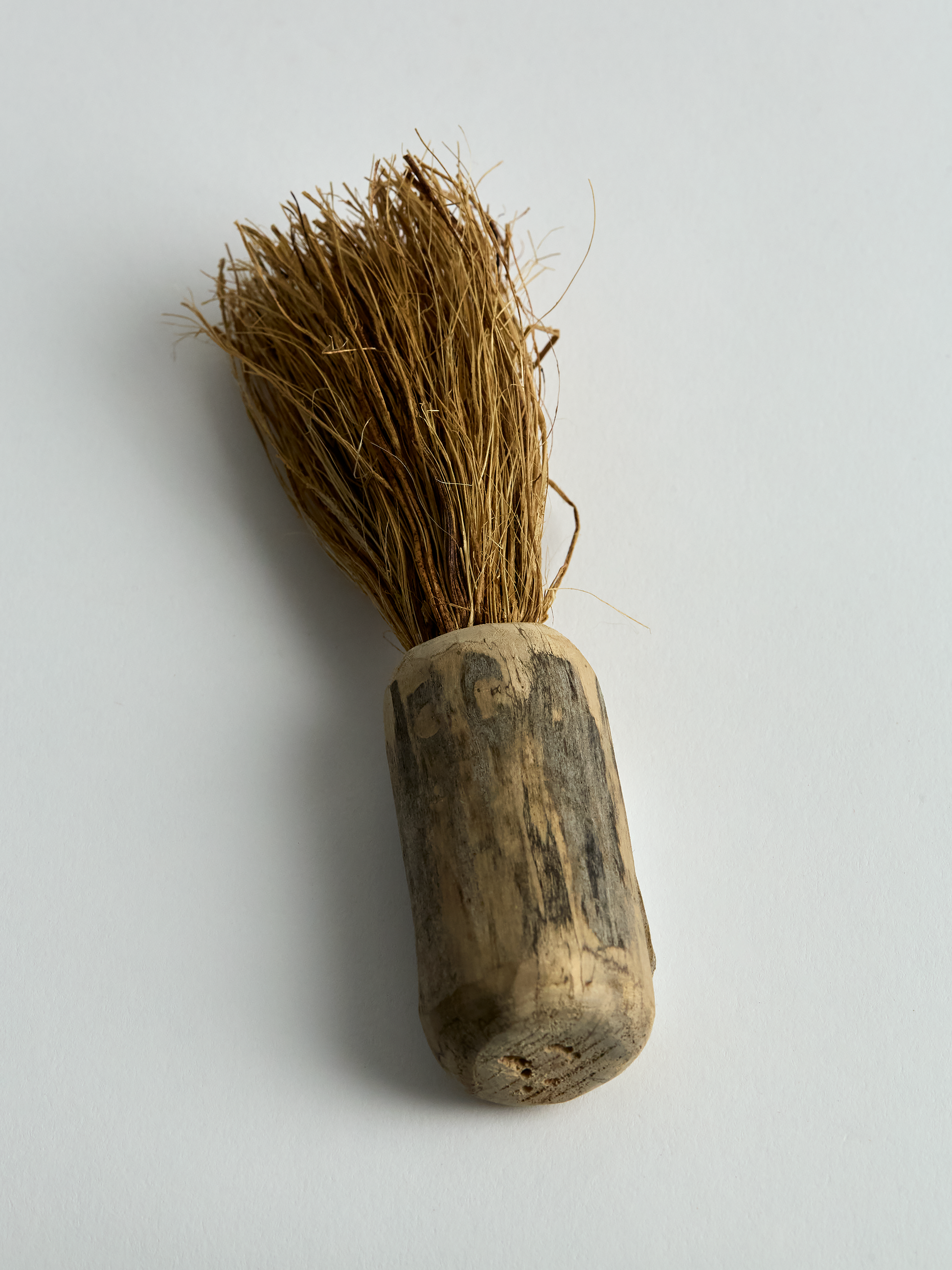 Traditional small wooden brush with bristle head on a light gray background