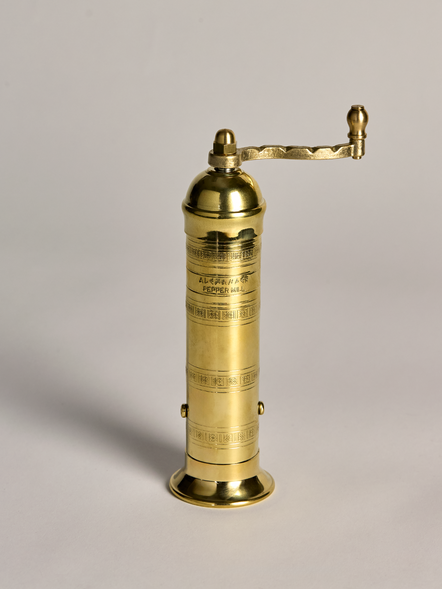 Brass pepper grinder on a light gray background