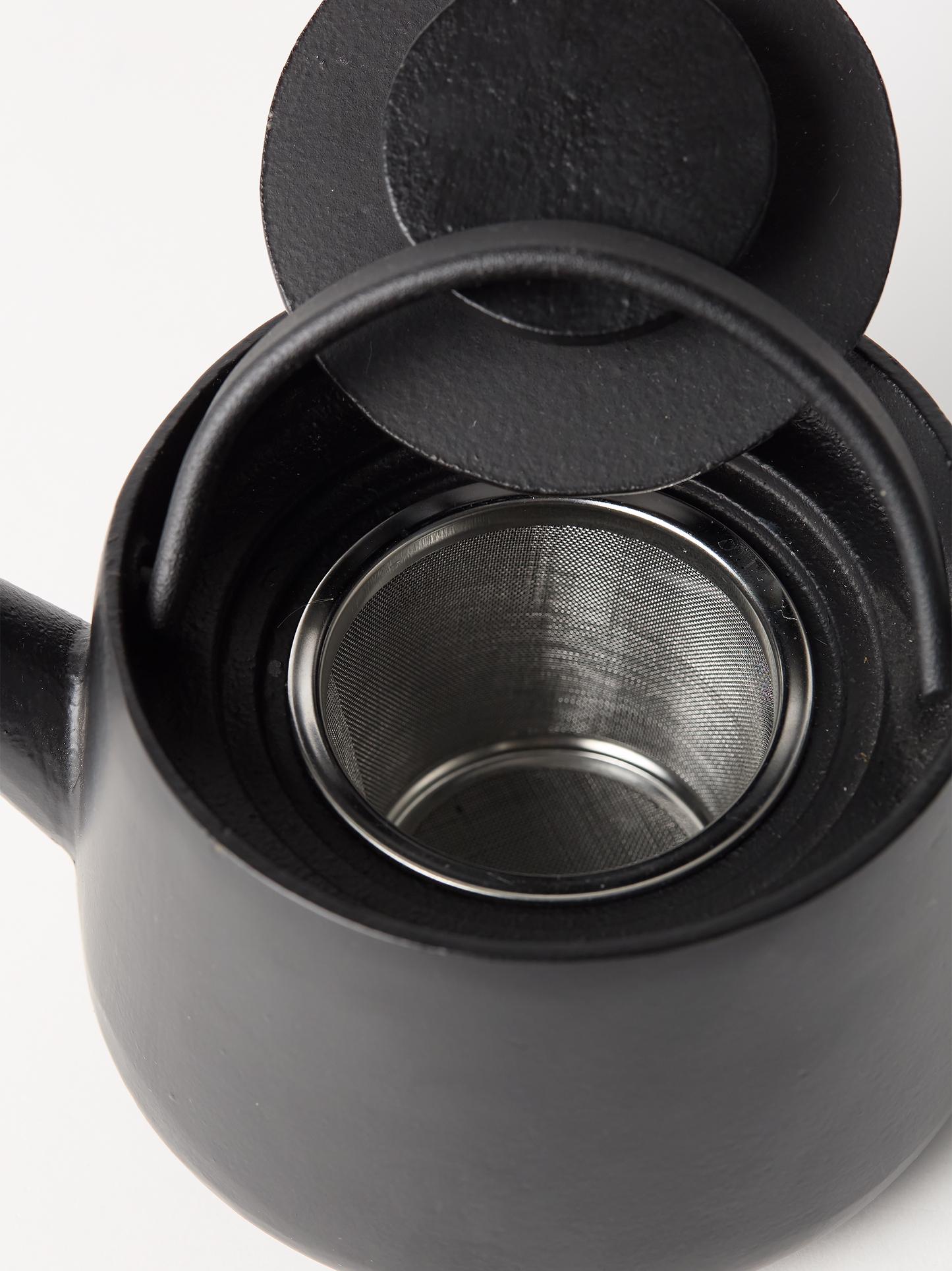 Black teapot with a metal filter on a white background