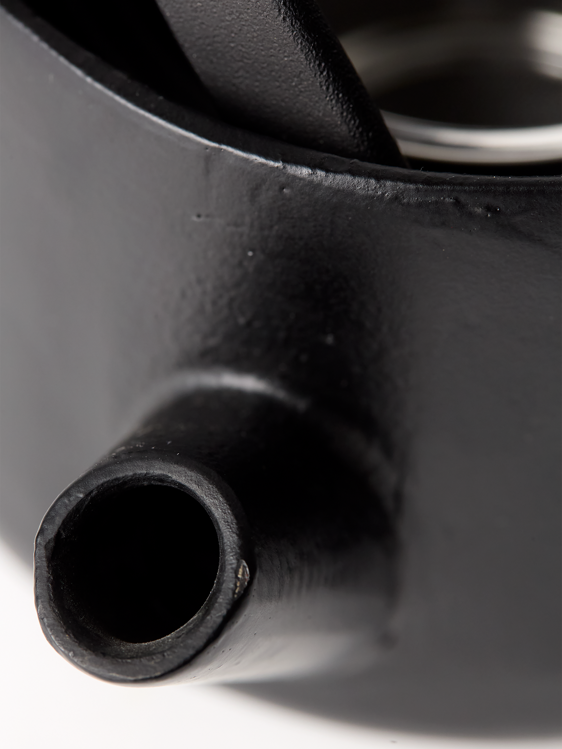 Close-up of a black metal teapot with a white background