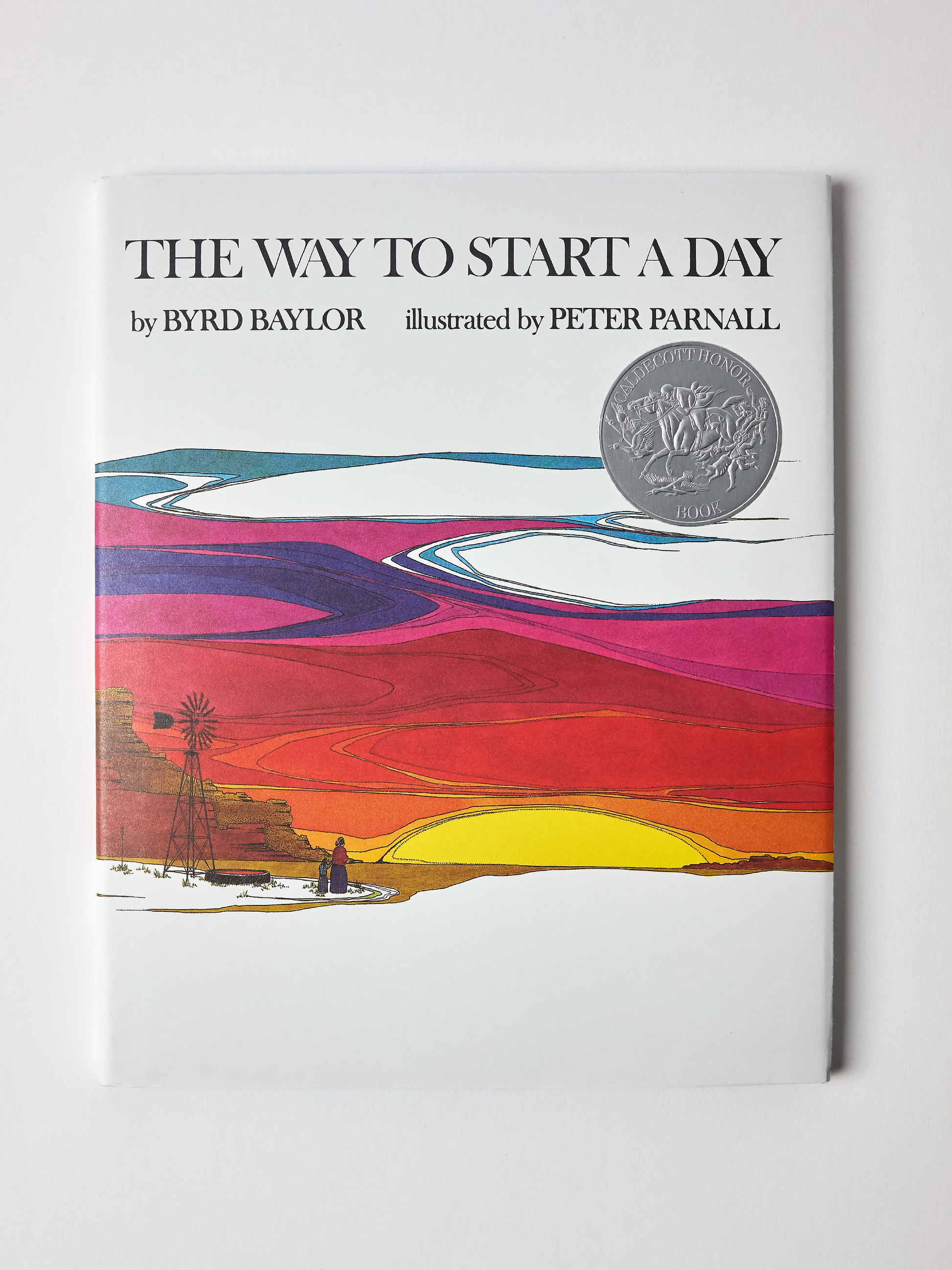 Book cover of 'The Way to Start a Day' by Byrd Baylor and Peter Parnall with colorful landscape illustration on a white background