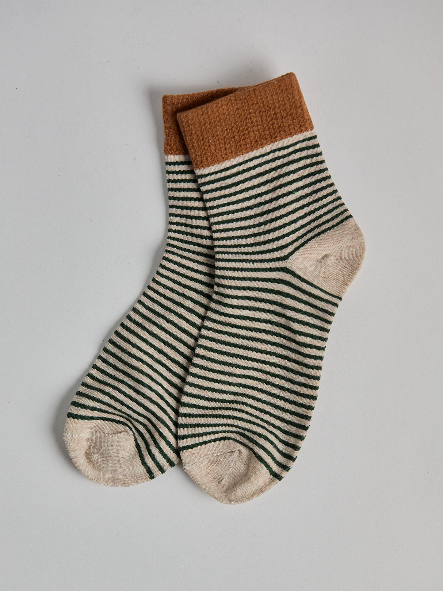 Striped socks with brown top and green and white stripes on a light gray background full image 1