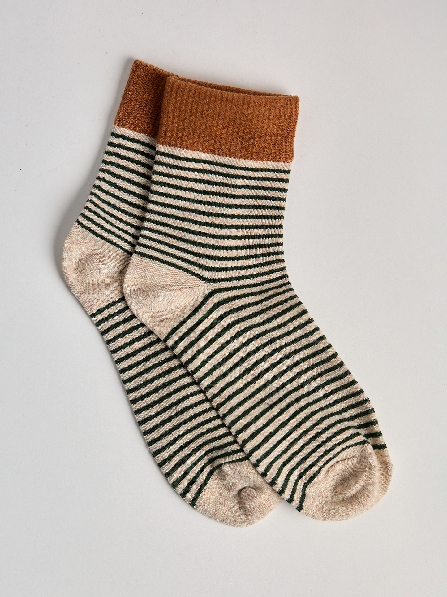 Striped socks with brown top and green and white stripes on a light gray background full image 2