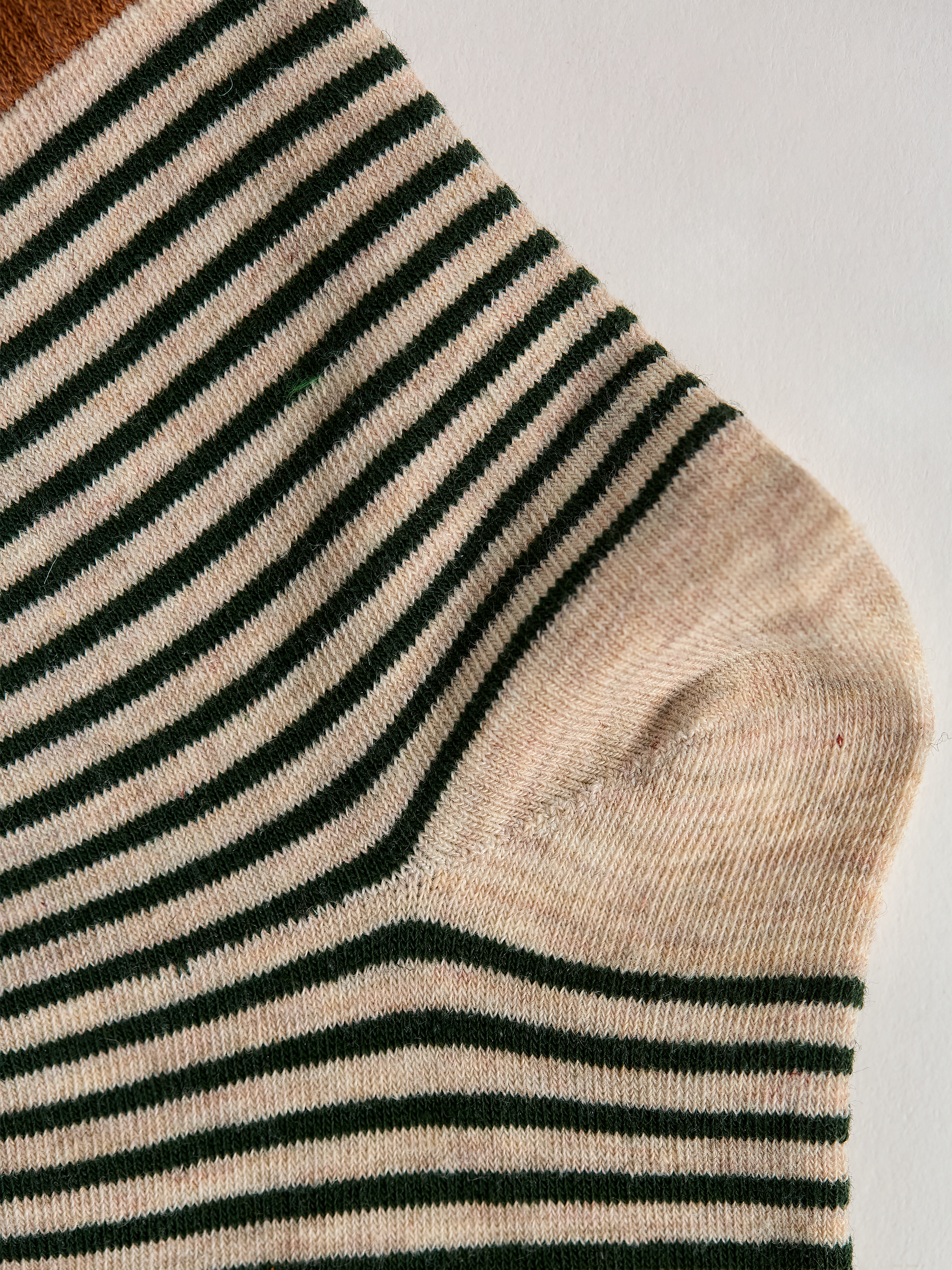 Close-up of striped sock heel with green and white stripes on a light gray background.