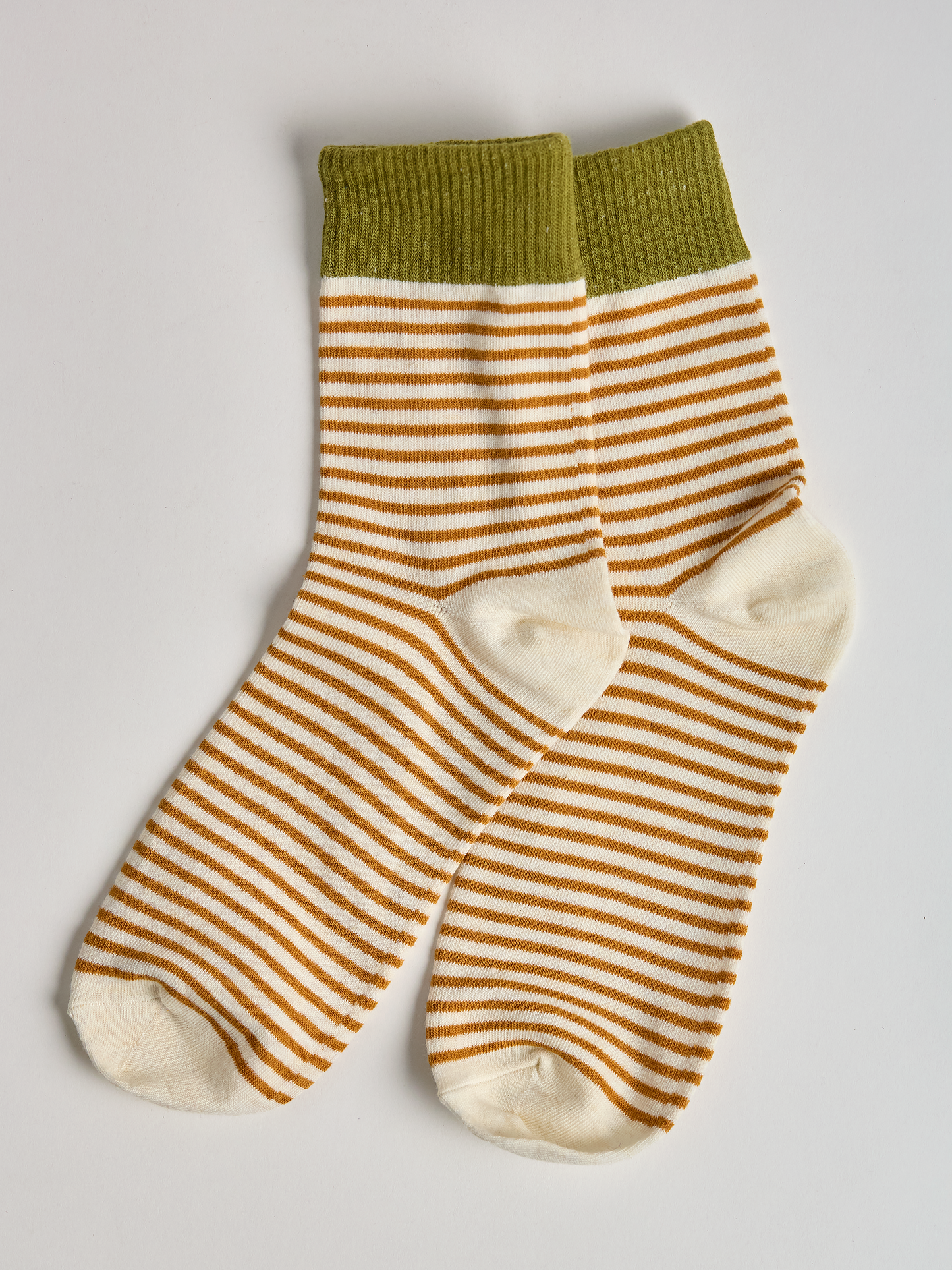 Striped socks with green top and gold and white stripes on a light gray background full image 2