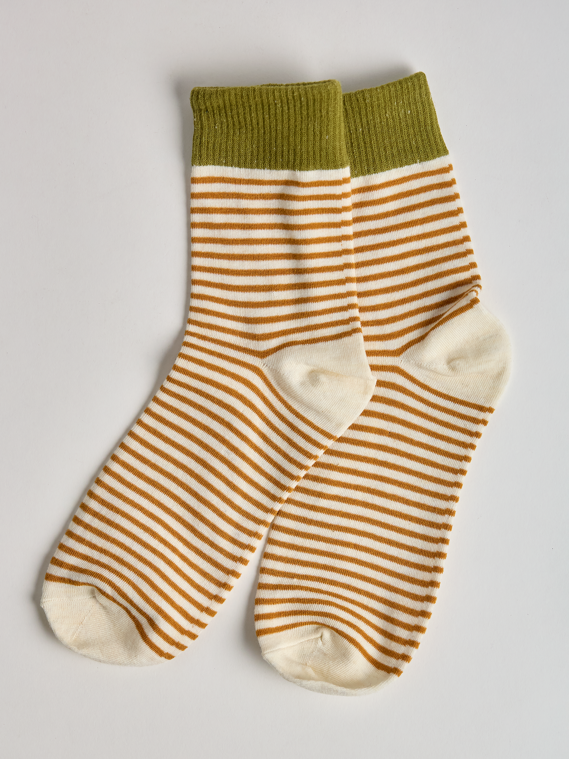 Striped socks with green top and gold and white stripes on a light gray background full image 2