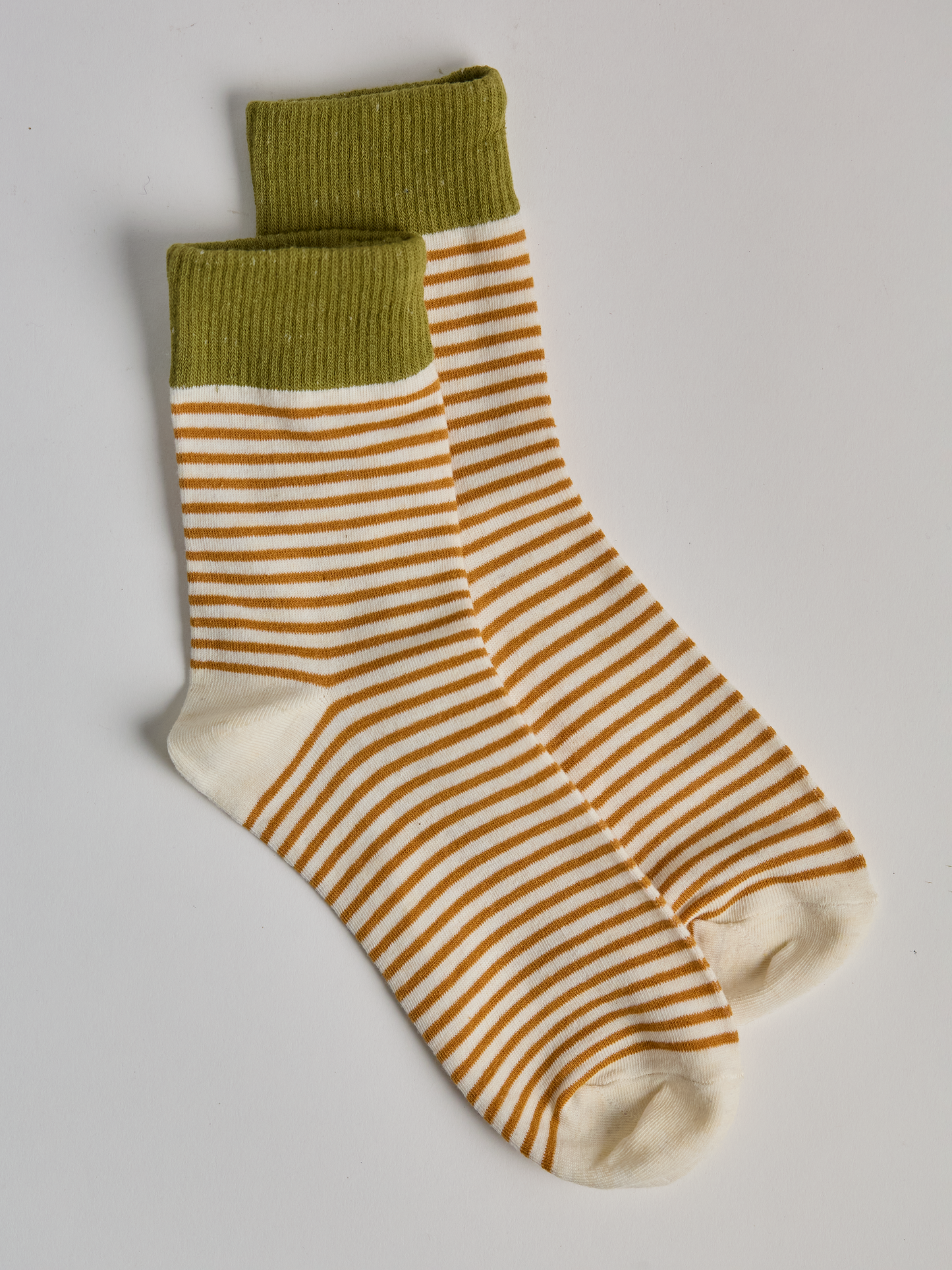 Striped socks with green top and gold and white stripes on a light gray background full image 1