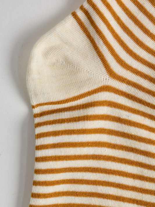 Close-up of striped sock heel with gold and white stripes on a light gray background.