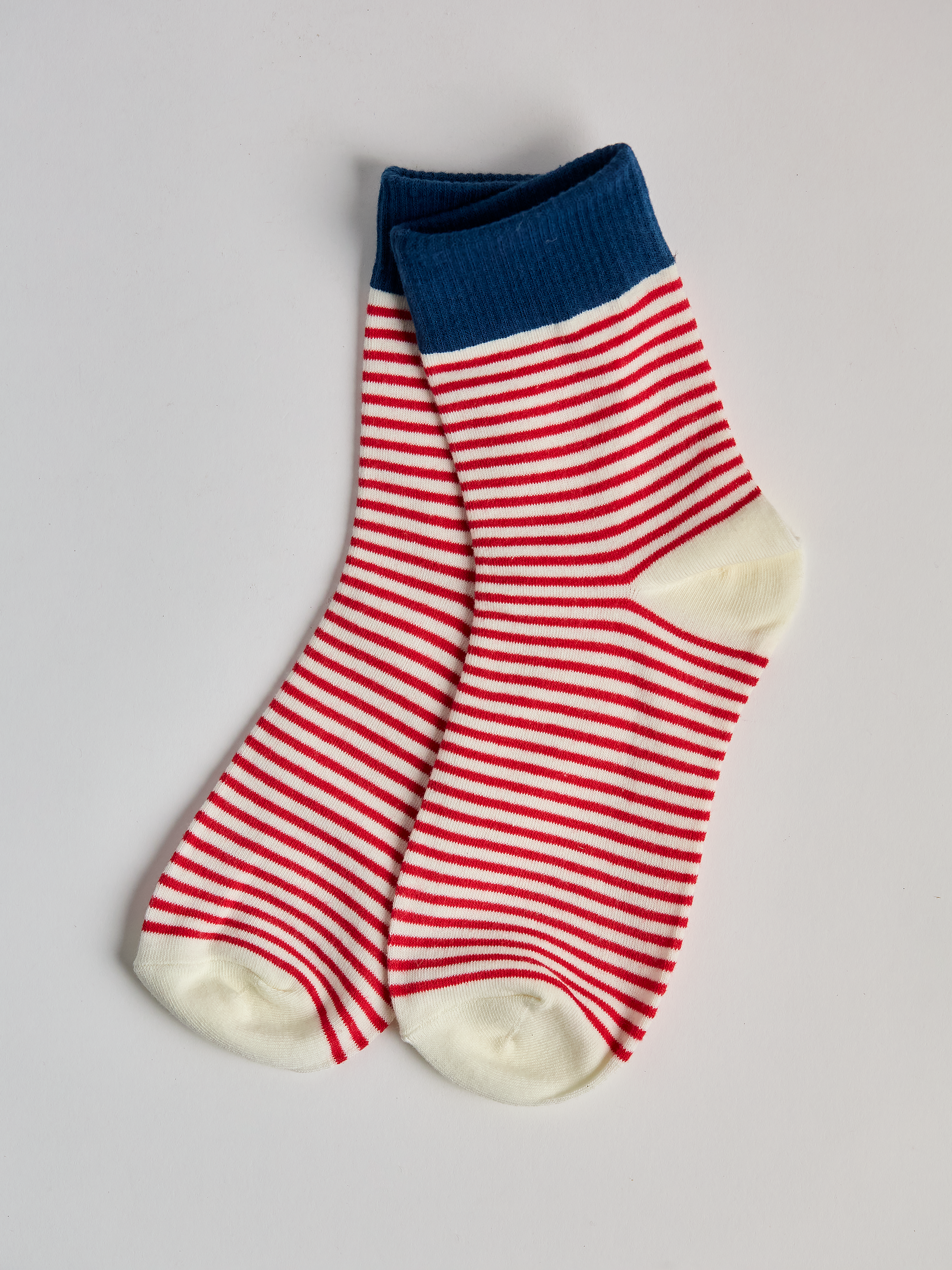 Striped socks with blue top and red and white stripes on a light gray background full image 1