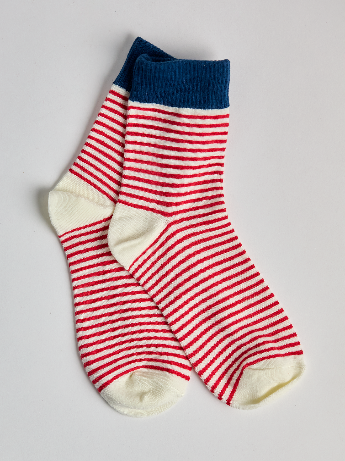 Striped socks with blue top and red and white stripes on a light gray background full image 2.