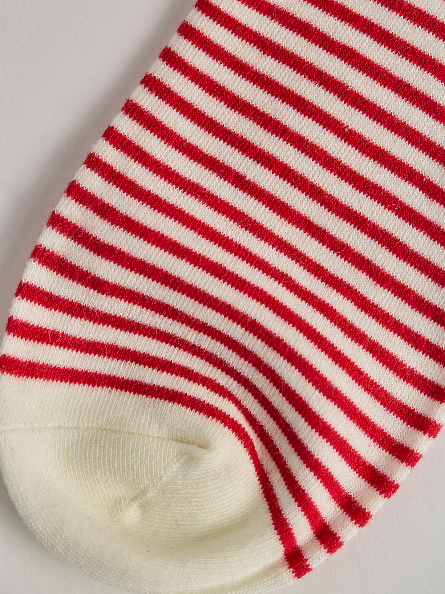 Close-up of striped sock toe with red and white stripes on a light gray background.