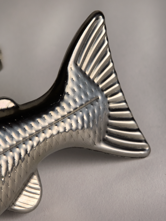 Close-up of a Metallic fish-shaped tail flask on a gray background